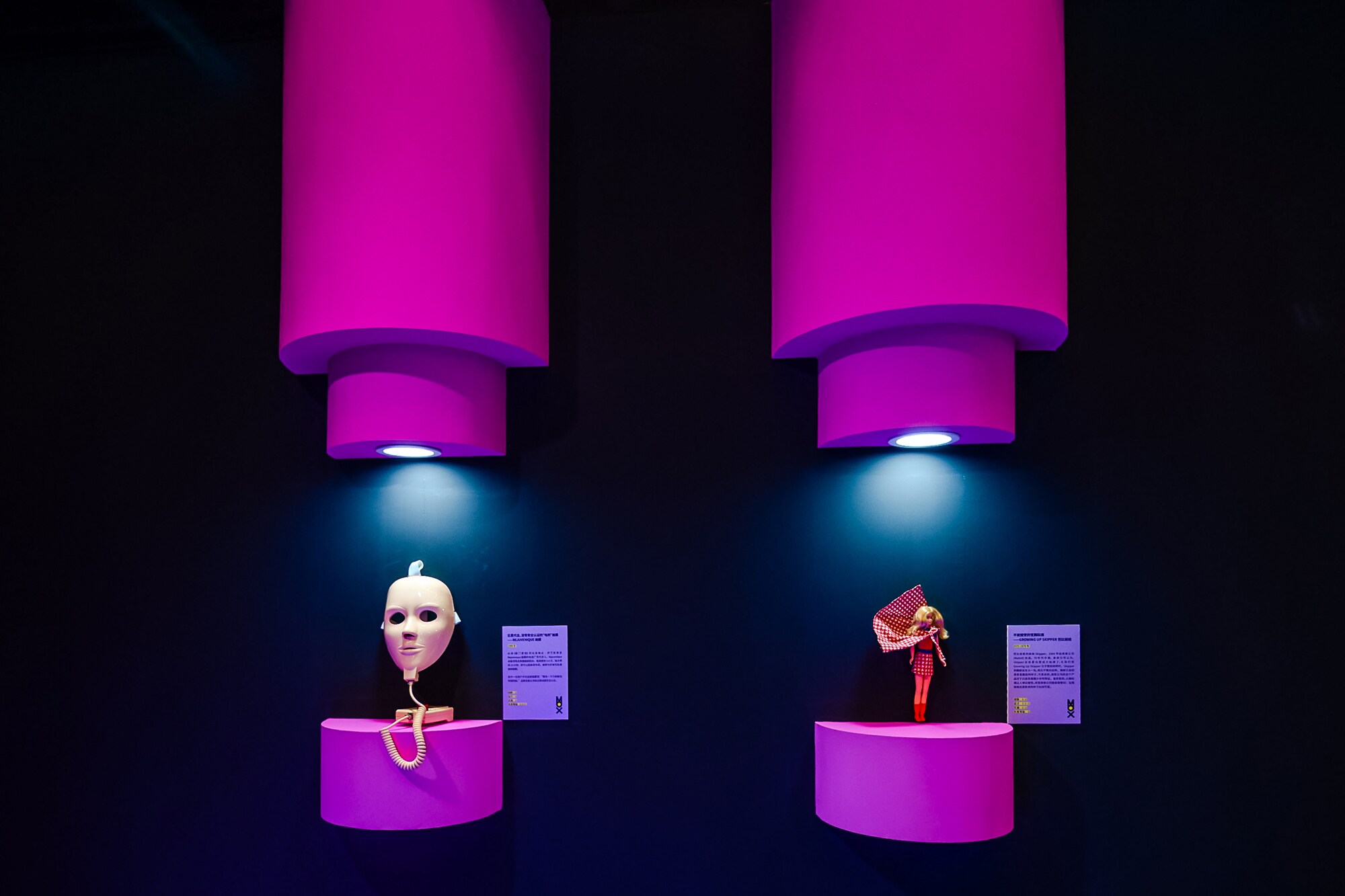 Eine Gesichtsmaske aus Plastik und eine Puppe als Ausstellungsexponate an einer Wand.