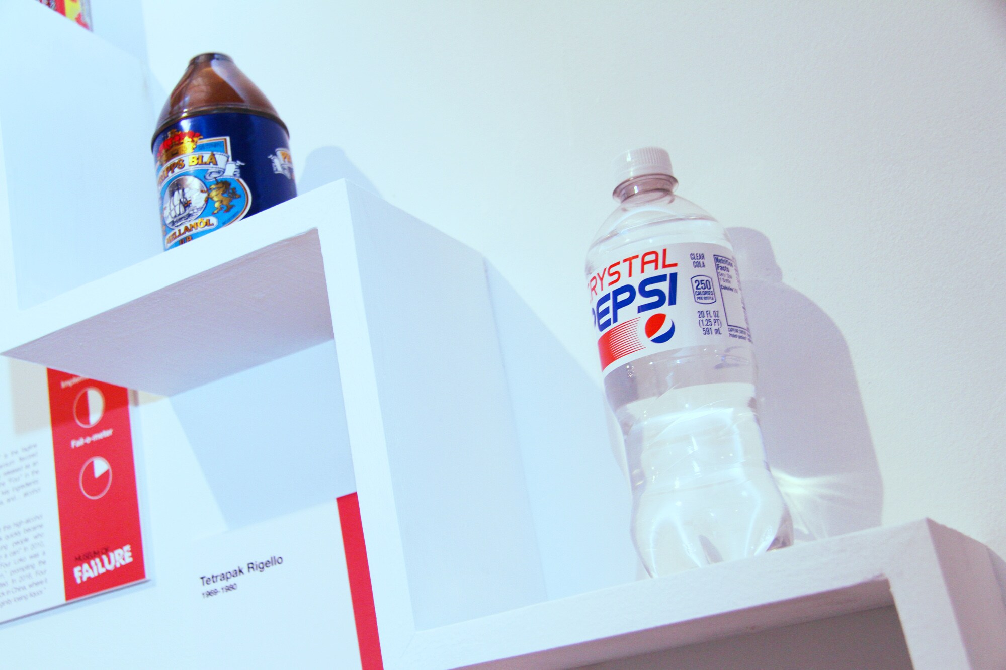 Eine Plastikflasche der Marke Crystal Pepsi mit durchsichtiger Flüssigkeit als Ausstellungsstück an einer Wand