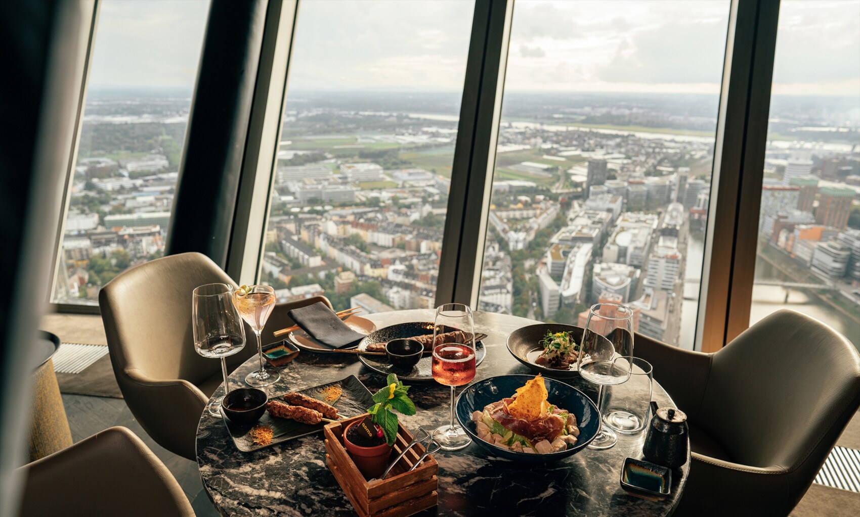 Ein gedeckter Marmortisch im Qomo vor Panoramafenstern mit Blick auf Düsseldorf