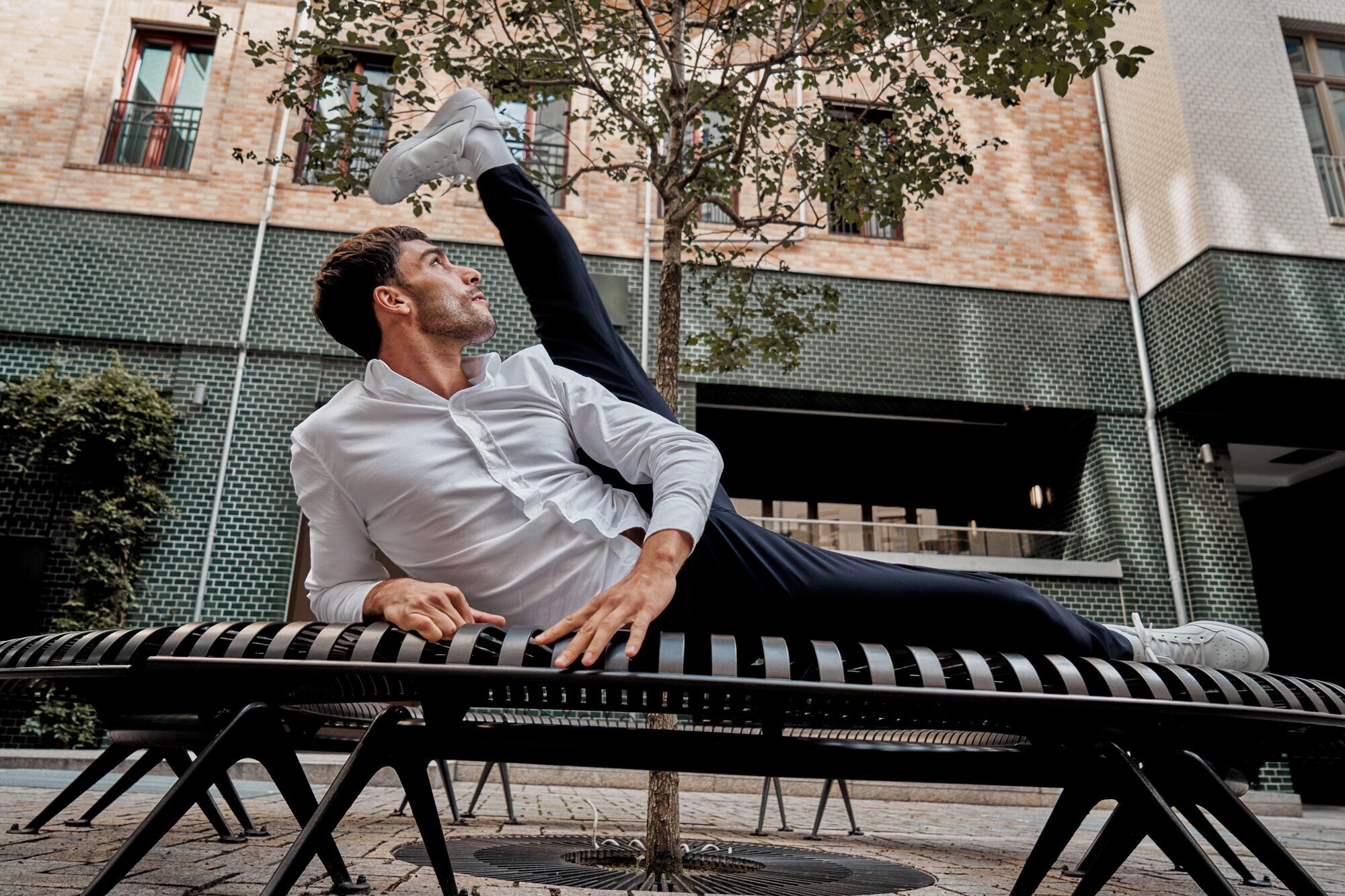 Ein Mann liegt auf einer Bank und streckt ein Bein in die Luft
