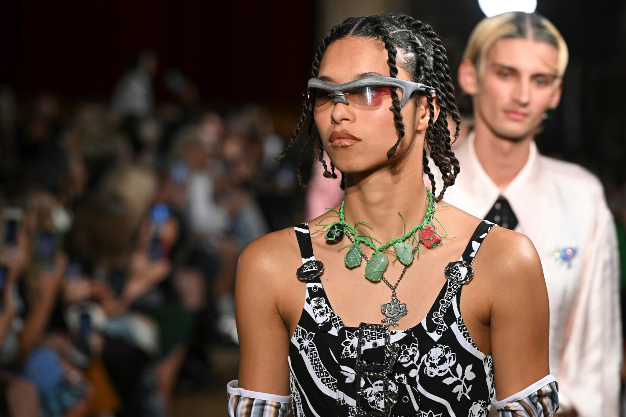Nahaufnahme eines Models in extravaganter Kleidung und futuristischer Sonnenbrille bei einer Modenschau