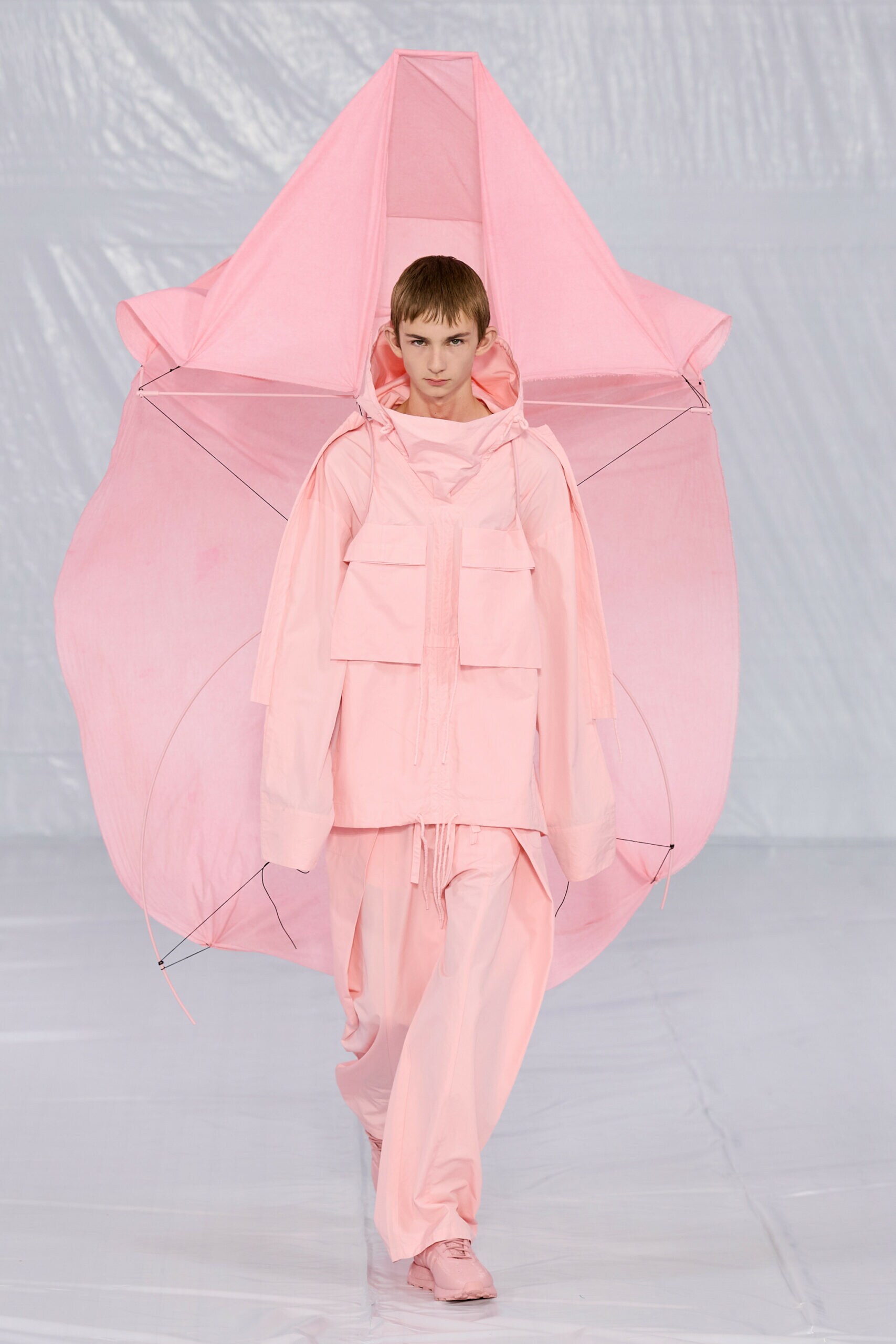 Ein Model mit rosafarbenem Outfit läuft einen Catwalk entlang.