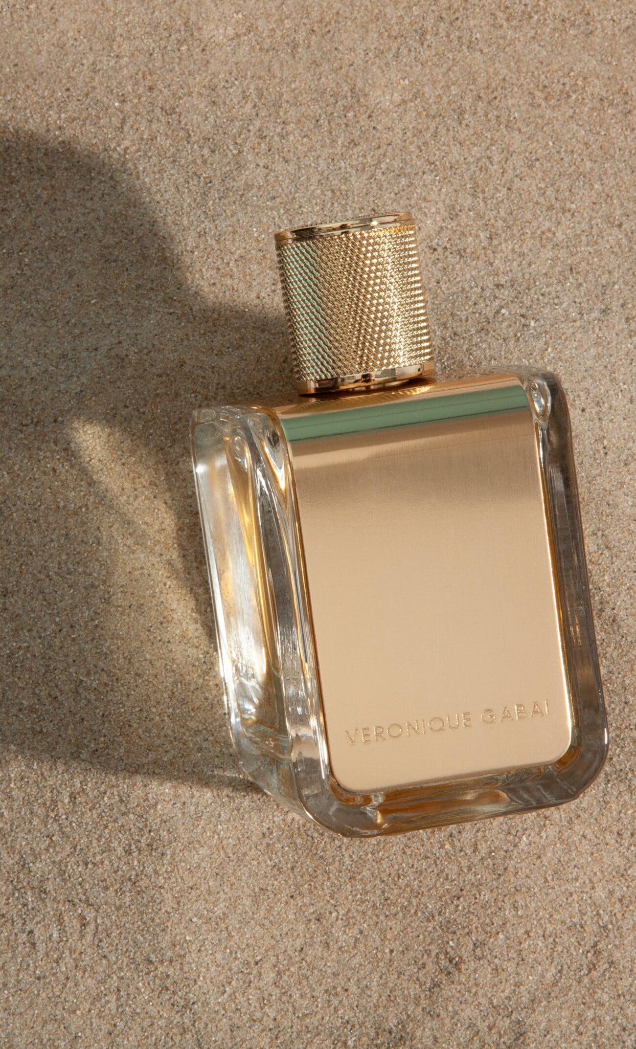 Ein Parfümflakon der Marke Veronique Gabai auf Sandboden Ein Parfümflakon der Marke Veronique Gabai auf Sandboden