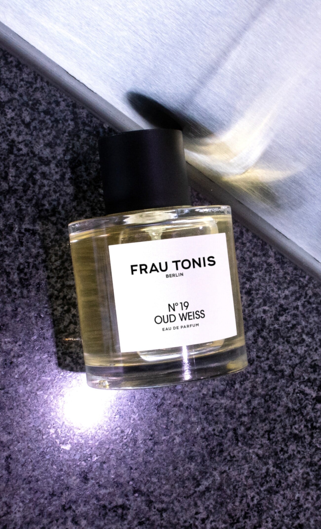 Ein Parfümflakon der Marke Frau Tonis auf grau-melierten Untergrund Ein Parfümflakon der Marke Frau Tonis auf grau-melierten Untergrund