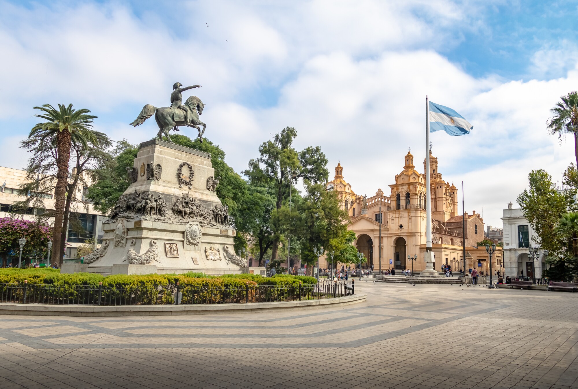 Reiterdenkmal auf einem Platz und argentinischer Flagge vor einer Kathedrale im Kolonialstil Reiterdenkmal auf einem Platz und argentinischer Flagge vor einer Kathedrale im Kolonialstil