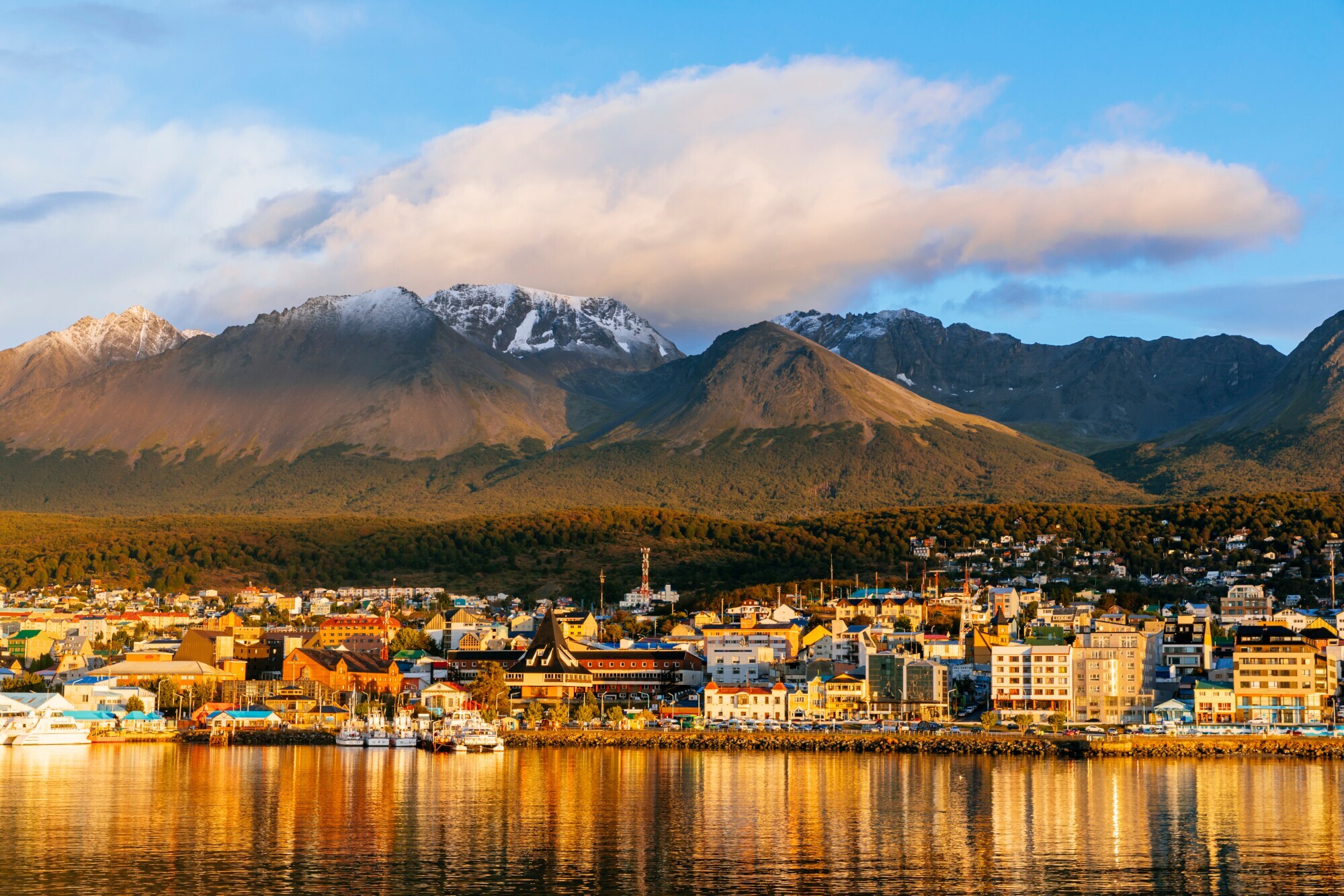 Stadtpanorama von Ushuaia am Wasser vor Bergkulisse im Sonnenuntergang Stadtpanorama von Ushuaia am Wasser vor Bergkulisse im Sonnenuntergang
