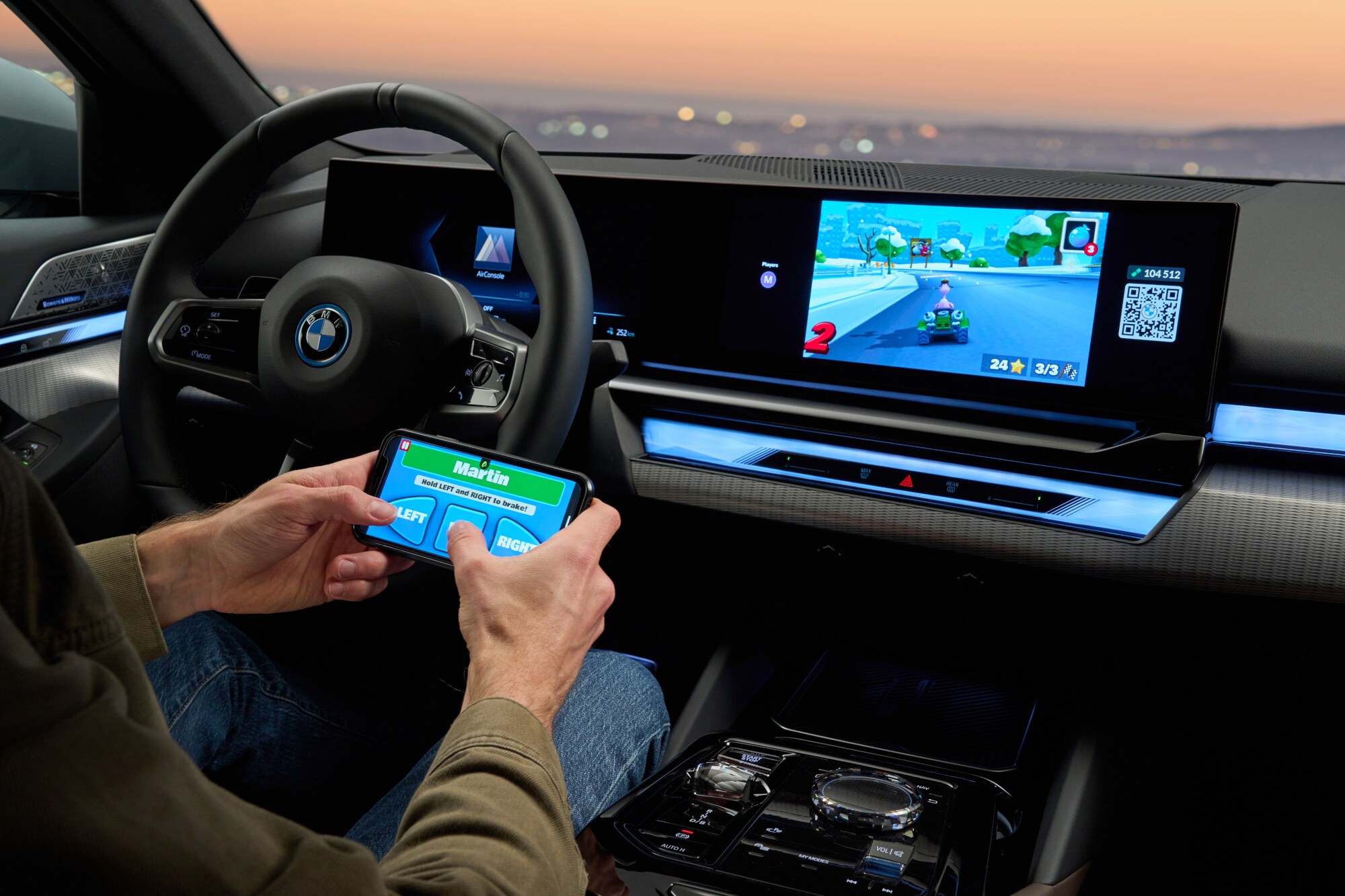 Eine Person sitzt im Auto und bedient über ihr Smartphone die AirConsole im BMW i5.