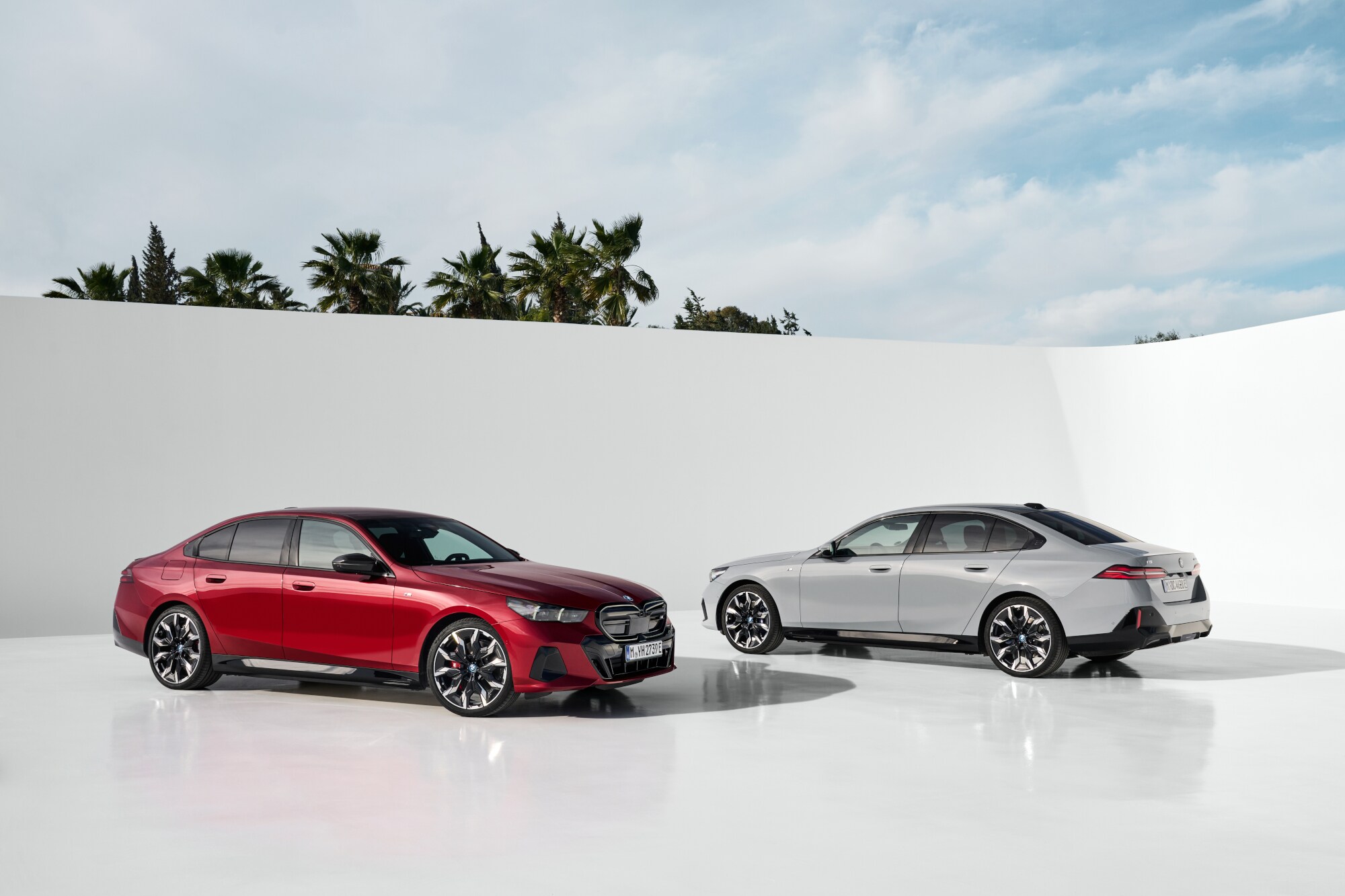 Zwei BMW i5 vor einer weißen Wand.