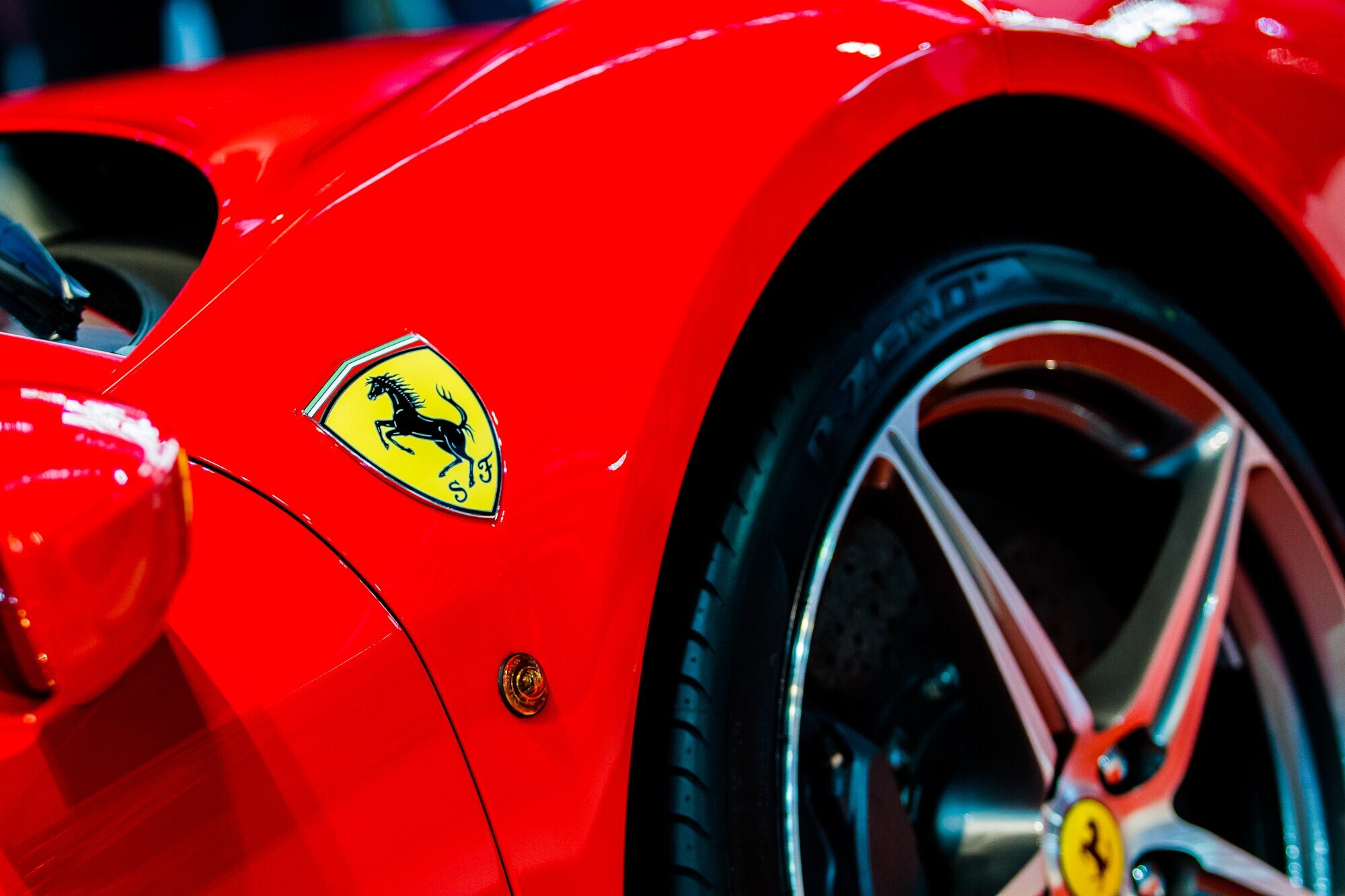 Detailaufnahme eines roten Rennwagens des Herstellers Ferrari mit dem Markenlogo eines sich aufbäumenden Pferdes in einem gelben Wappen