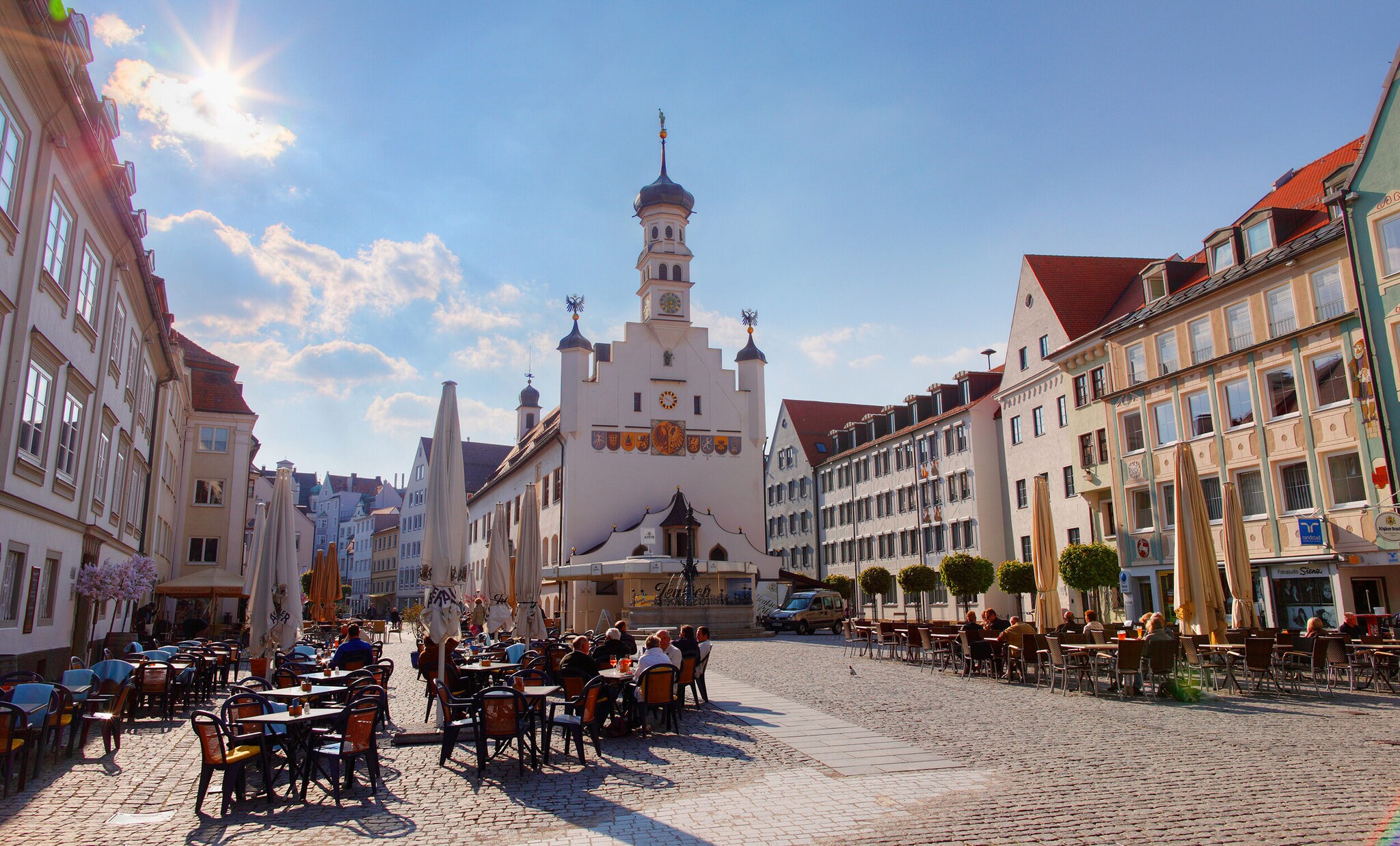 Altstadt von Kempten mit Personen, die in Cafés auf dem Marktplatz vor einer Kirche sitzen Altstadt von Kempten mit Personen, die in Cafés auf dem Marktplatz vor einer Kirche sitzen