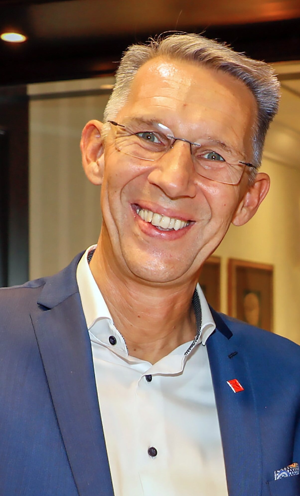 Porträt von Timo Gloxin, der einen blauen Anzug trägt und in die Kamera strahlt Porträt von Timo Gloxin, der einen blauen Anzug trägt und in die Kamera strahlt