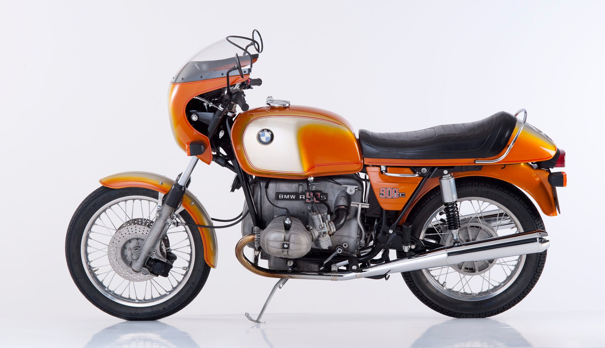 Produktfoto eines BMW-Motorrad R 90 S in orangefarbenem Design vor weißem Hintergrund