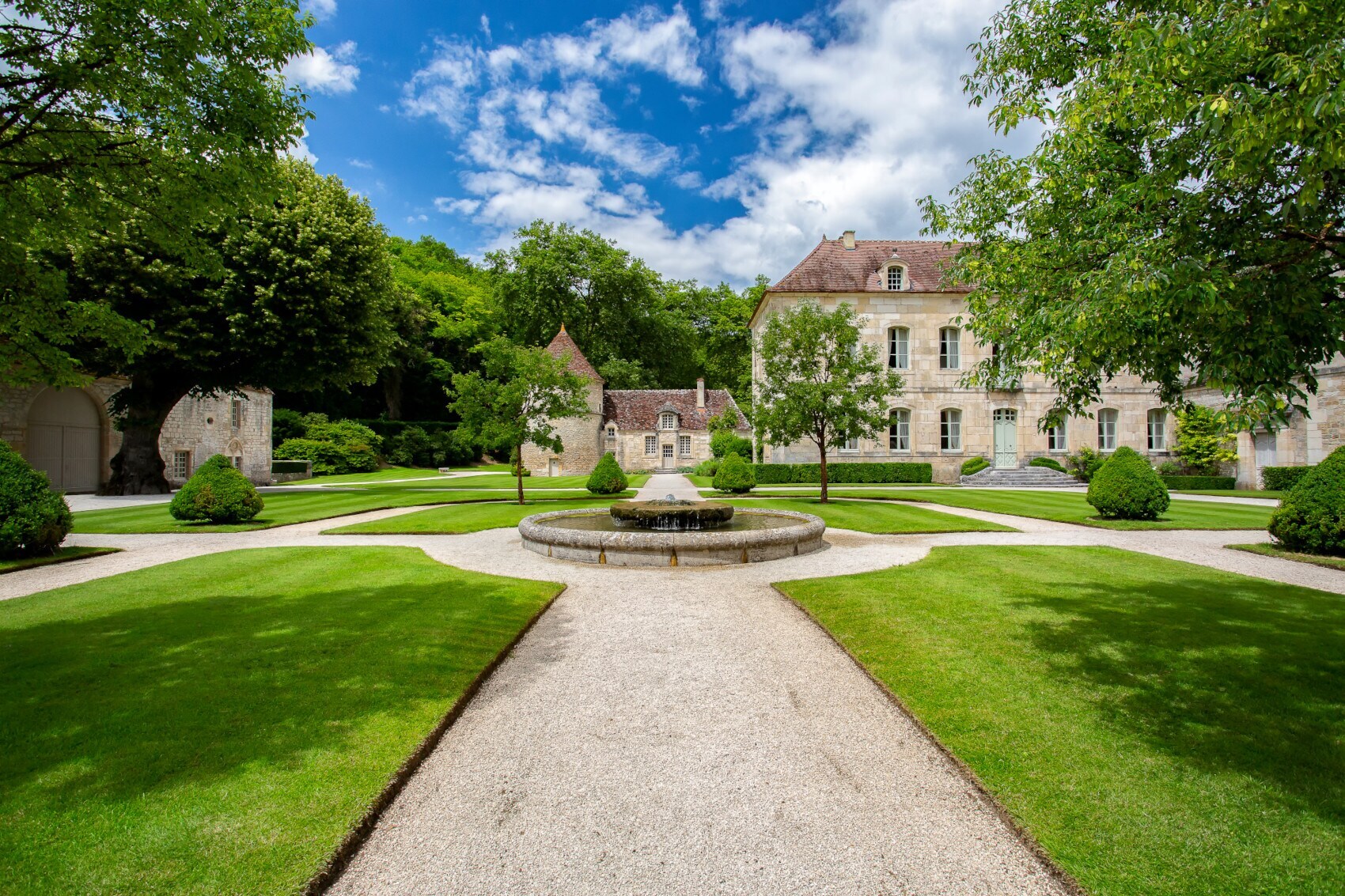Landschaftsgarten mit Rasenflächen, Wegen und Springbrunnen innerhalb einer Klosteranlage