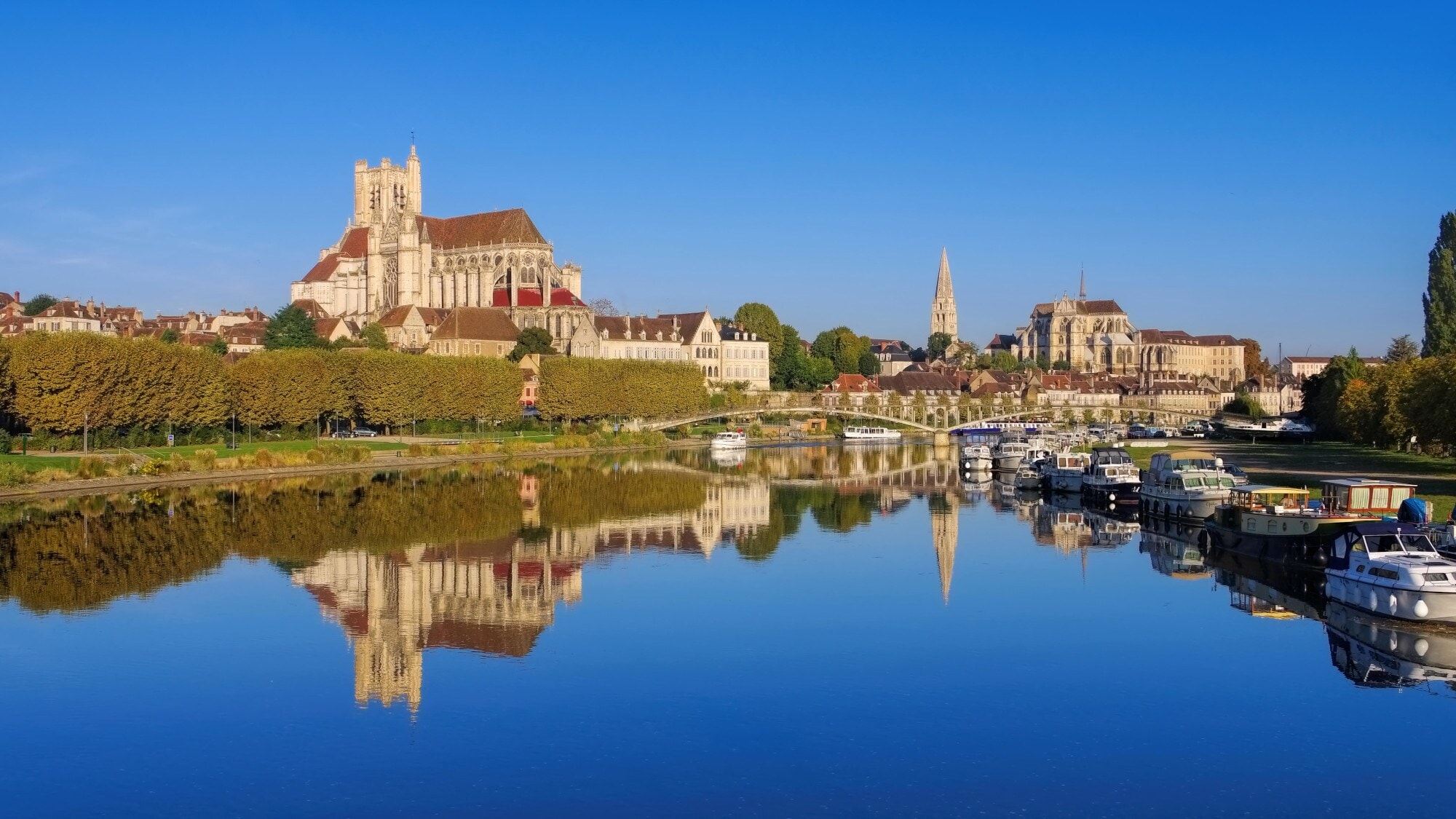 Stadtpanorma von Auxerre mit Kathedrale und Abtei, davor Boote auf einem Fluss Stadtpanorma von Auxerre mit Kathedrale und Abtei, davor Boote auf einem Fluss