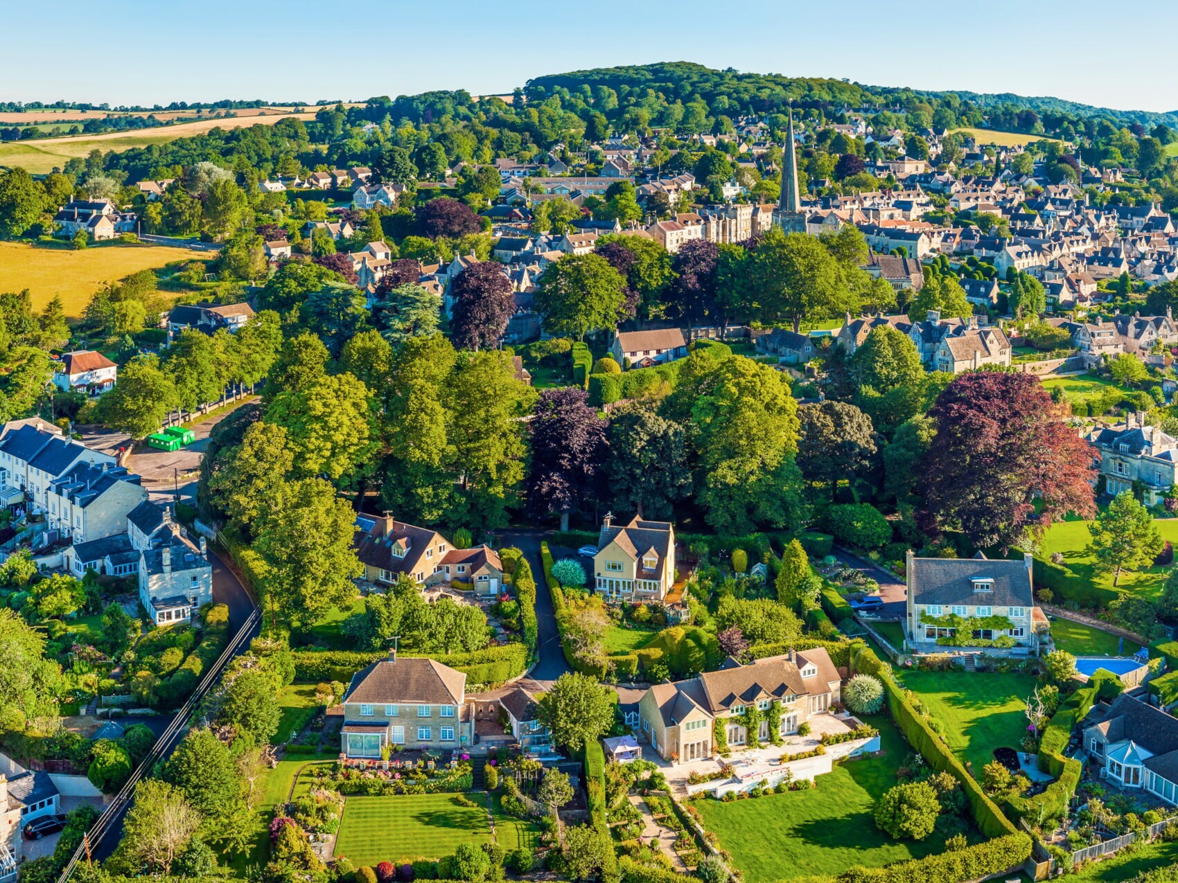 Panorama-Luftaufnahme einer malerischen Landschaft mit Landhäusern umgeben von grünen Hügeln Panorama-Luftaufnahme einer malerischen Landschaft mit Landhäusern umgeben von grünen Hügeln