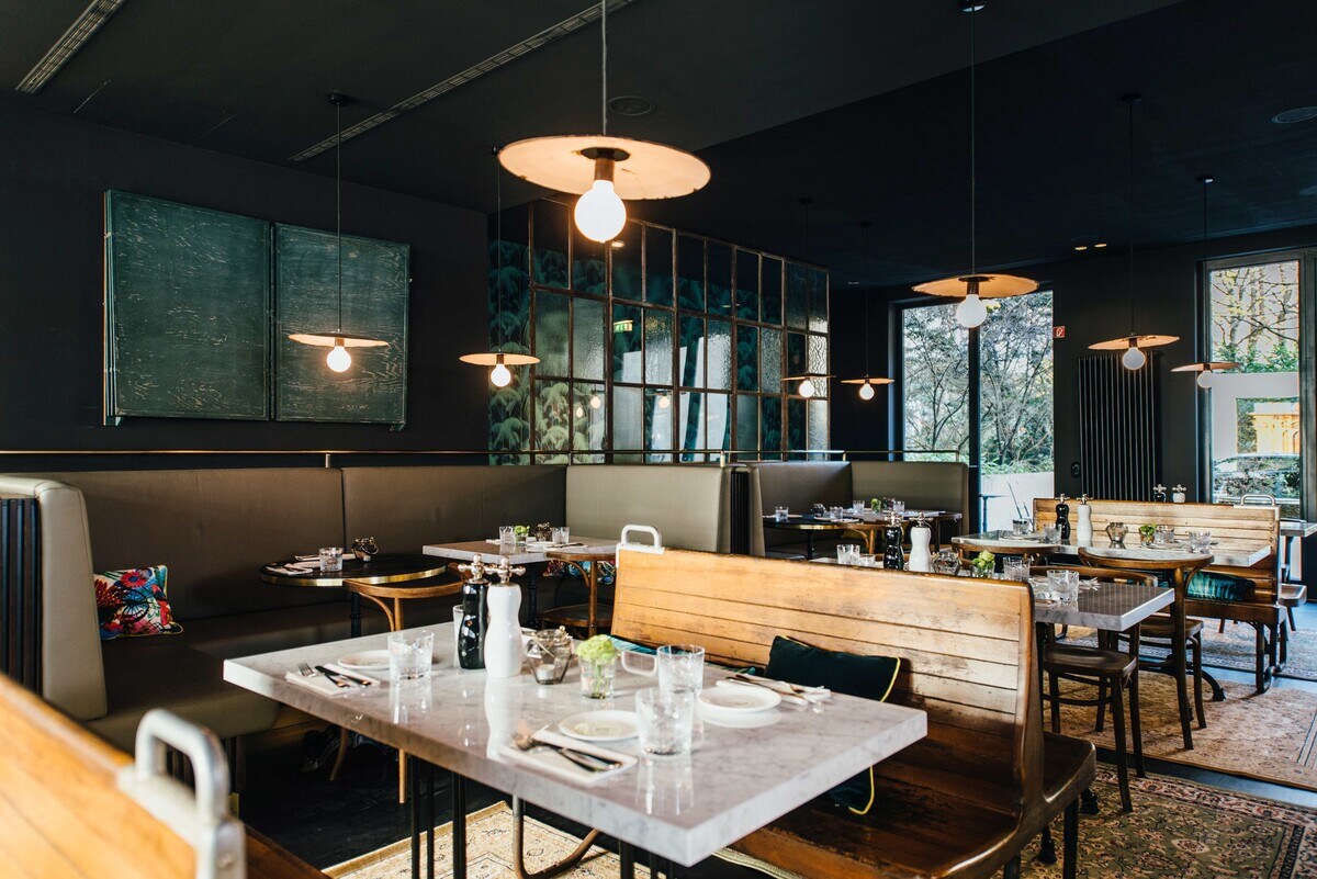 Holzbänke und gedeckte Tische in der Brasserie Colette in München
