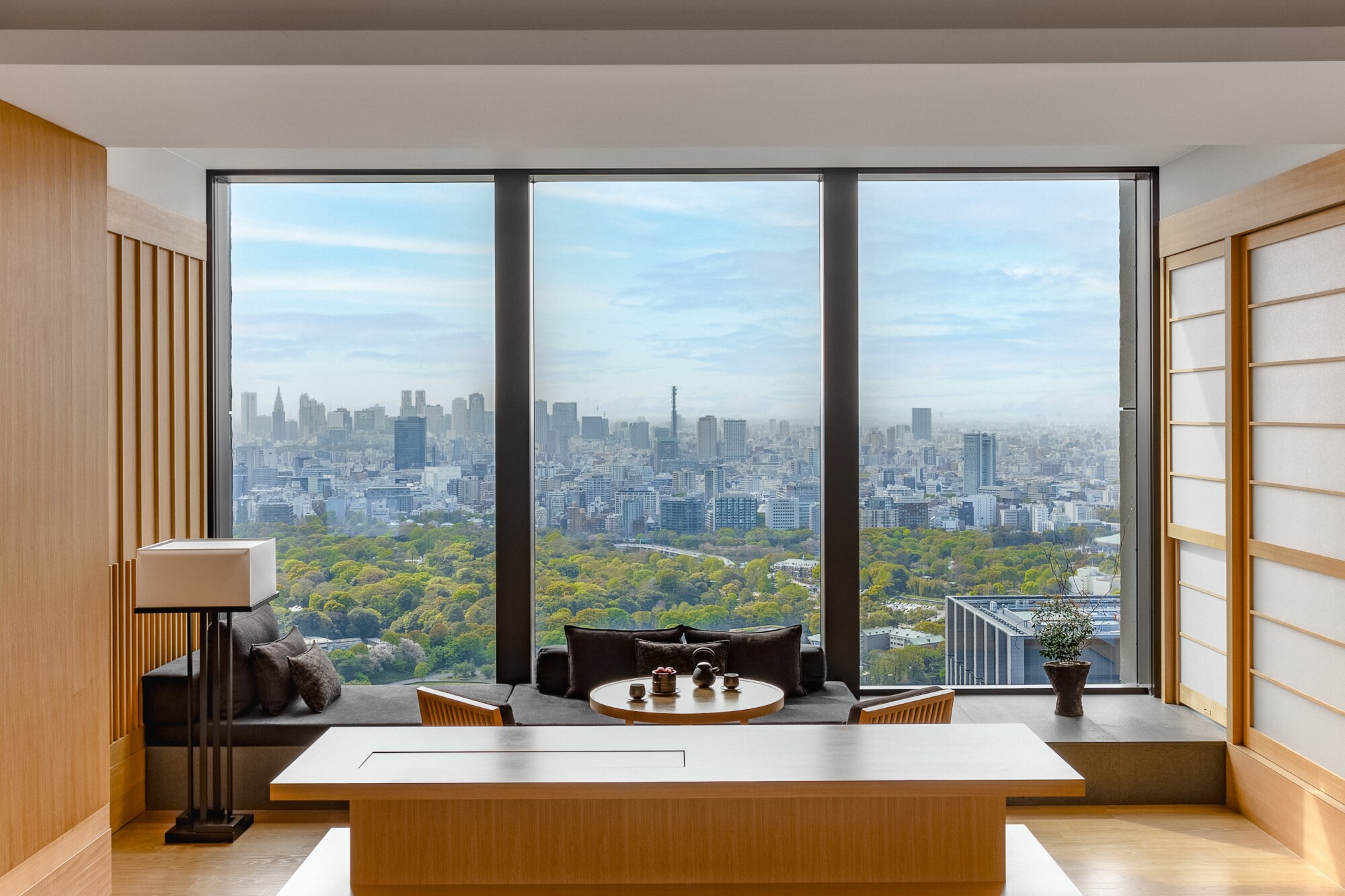 Hotelsuite im japanischen Stil mit Blick durch ein bodentiefes Panoramafenster auf die Skyline von Tokio