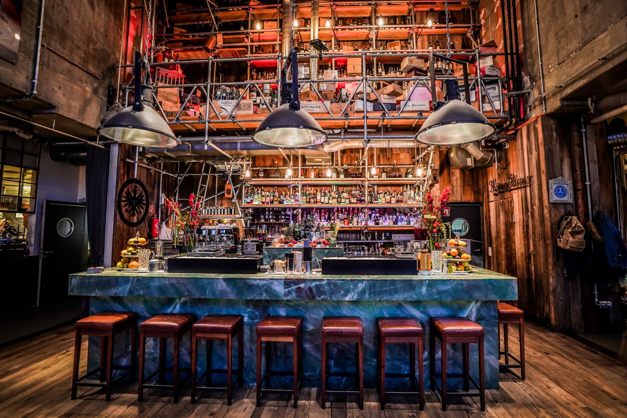 Blick auf eine Bar im Marmorlook, davor Barhocker Blick auf eine Bar im Marmorlook, davor Barhocker