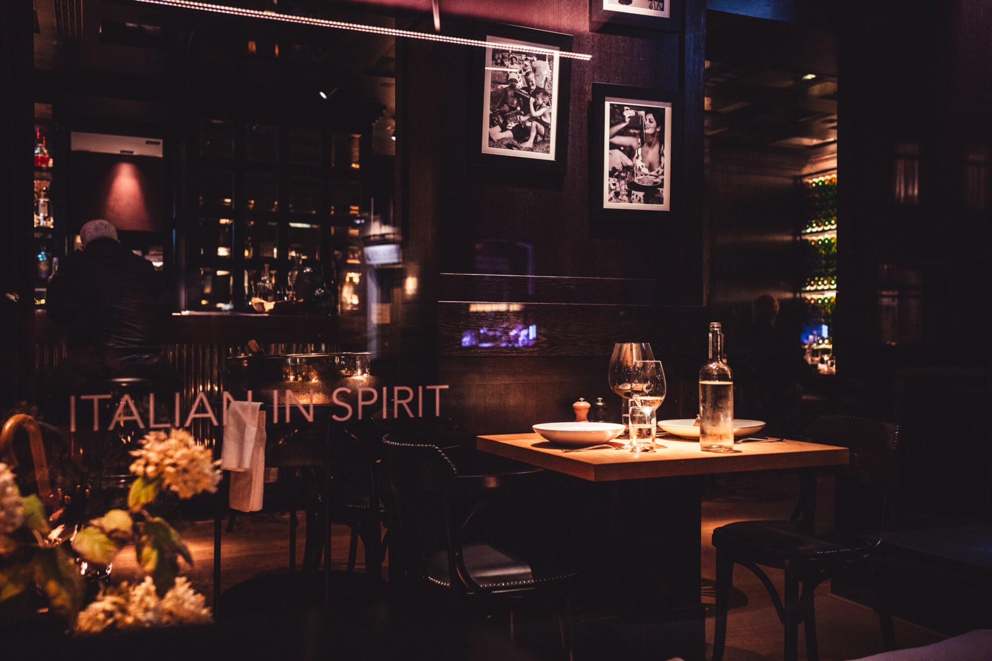 Blick von außen durch eine Fensterscheibe in ein italienisches Restaurant mit gedämpfter Beleuchtung