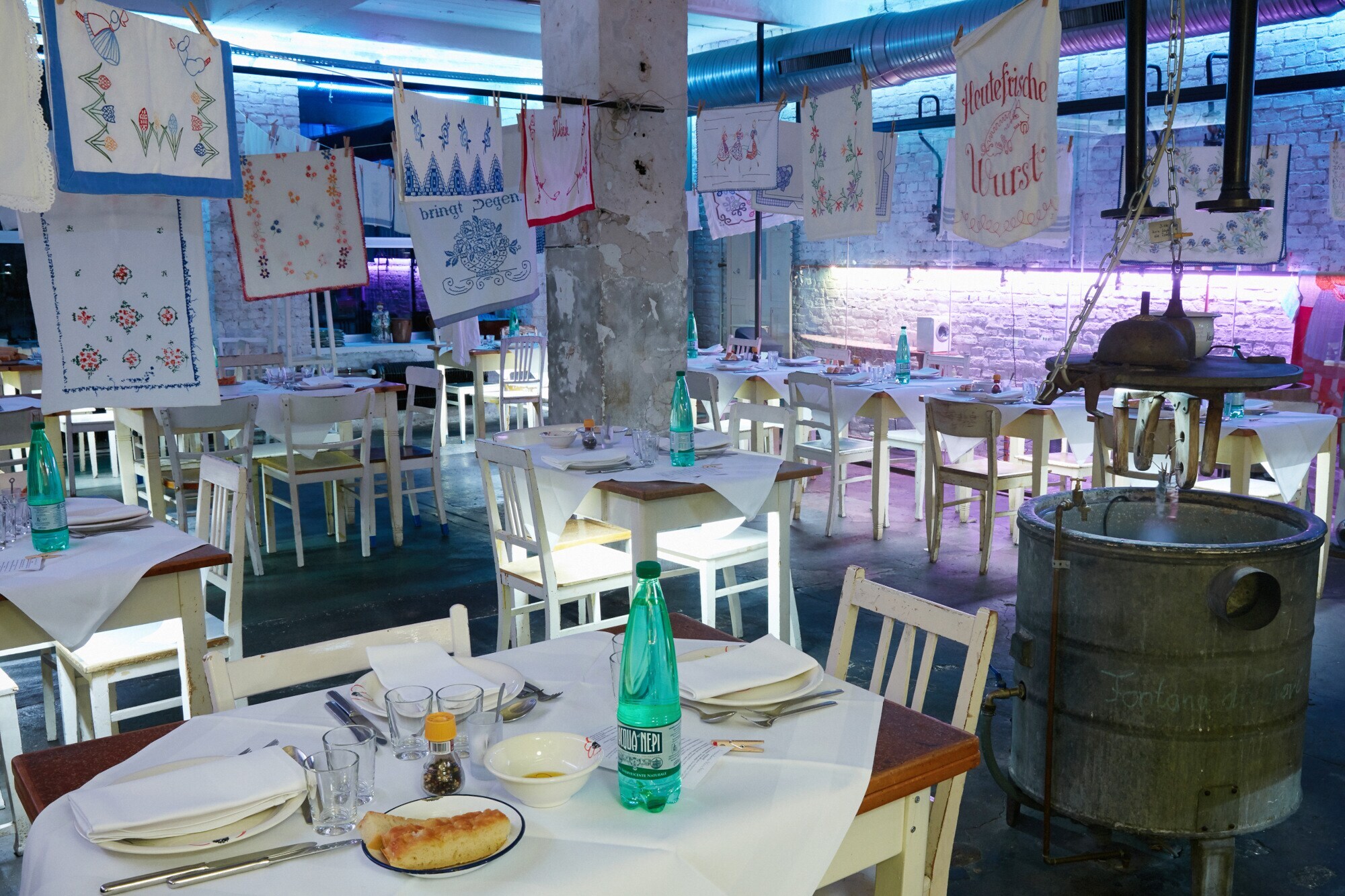 Raum mit Stühlen an gedeckten Tischen mit Wäscheleinen quer durchs Zimmer