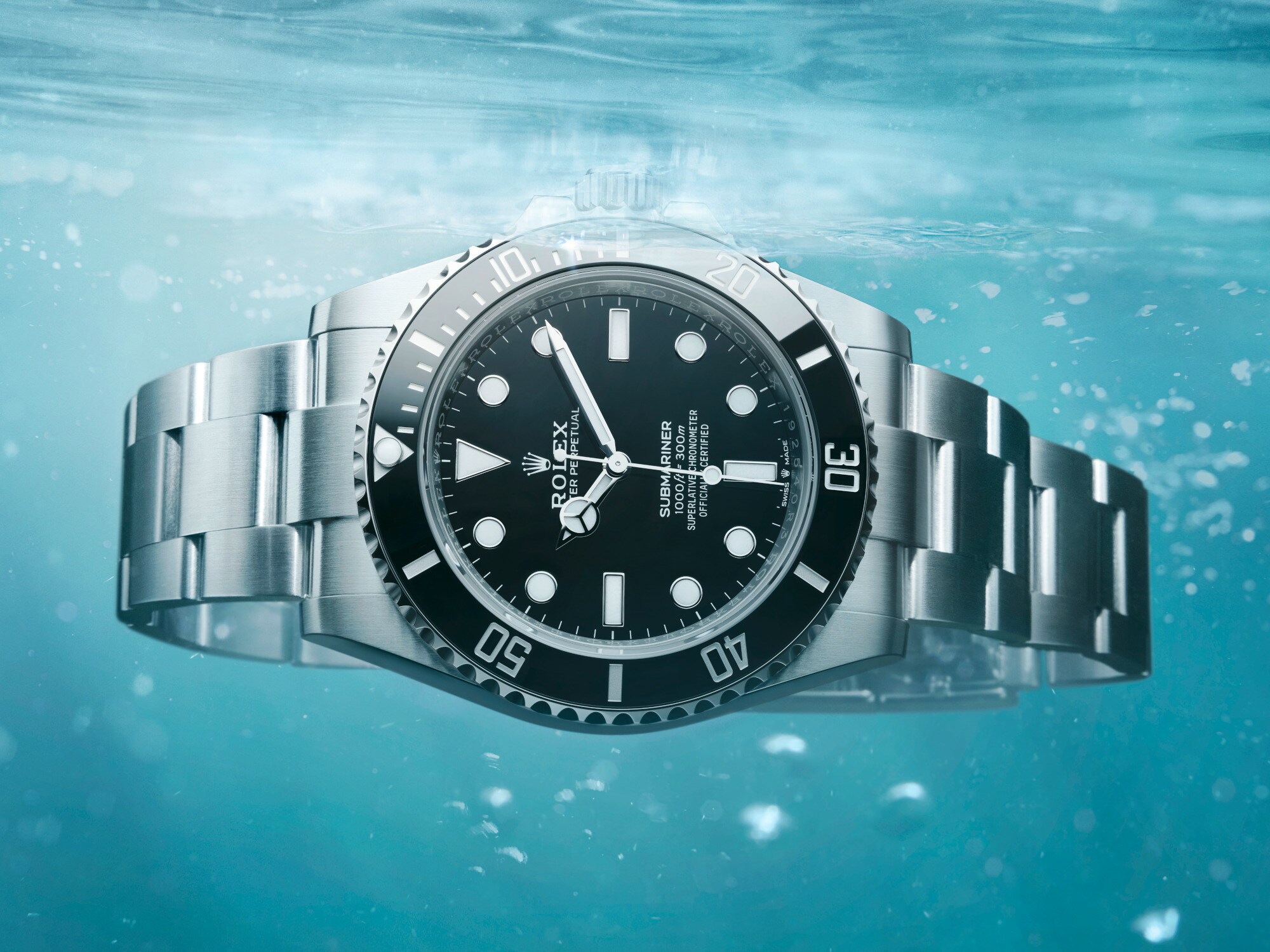 Close-up einer im Wasser schwebenden Rolex-Uhr mit schwarzem Zifferblatt und metallenem Gliederarmband Close-up einer im Wasser schwebenden Rolex-Uhr mit schwarzem Zifferblatt und metallenem Gliederarmband