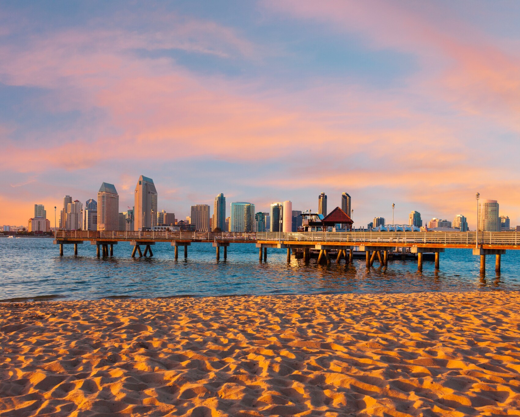 Skyline von San Diego mit einem Pier am Sandstrand im Vordergrund bei Sonnenuntergang Skyline von San Diego mit einem Pier am Sandstrand im Vordergrund bei Sonnenuntergang