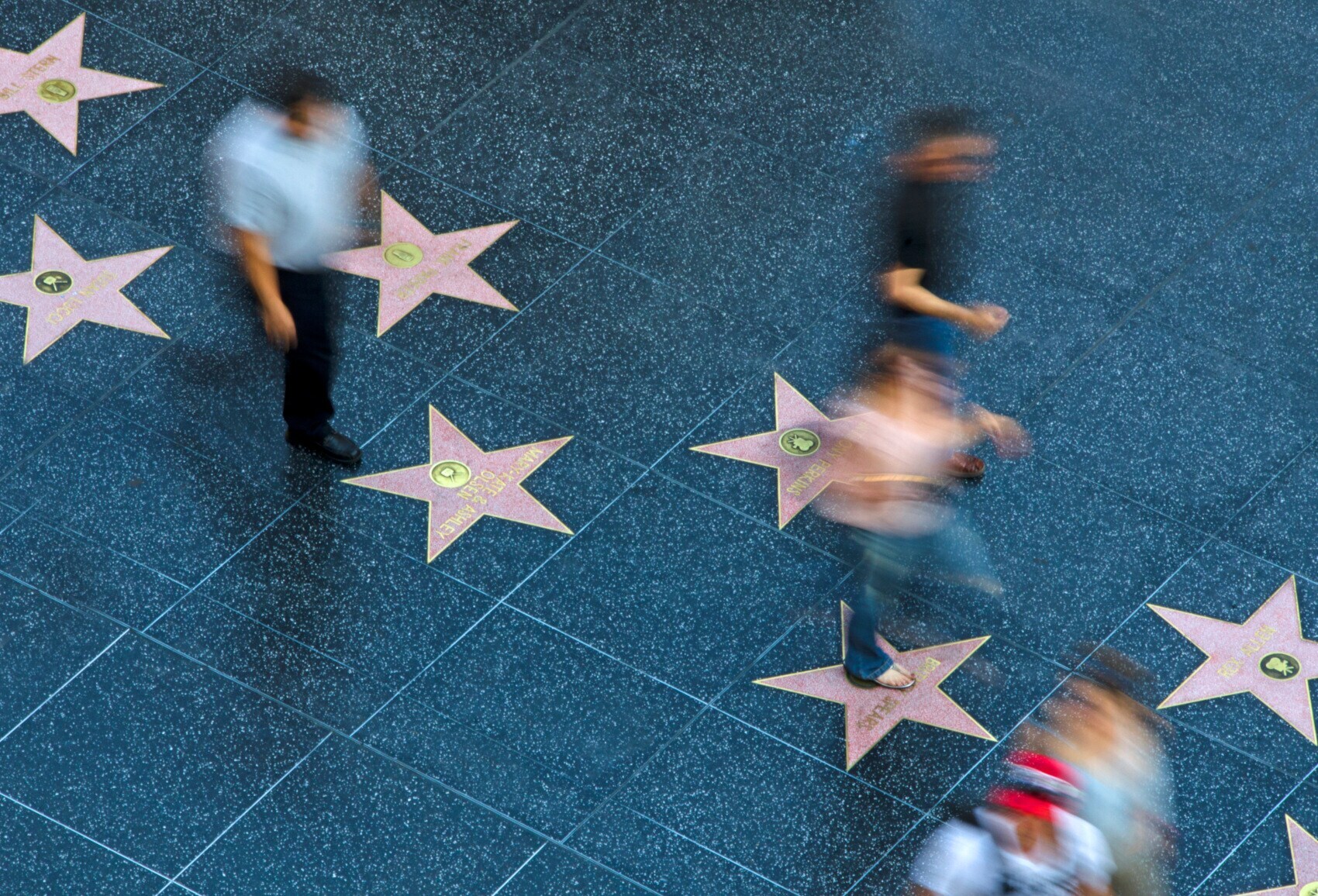 Fußgänger in der Bewegungsunschärfe laufen über die Sterne der Hollywoodstars auf dem Gehweg Walk of Fame