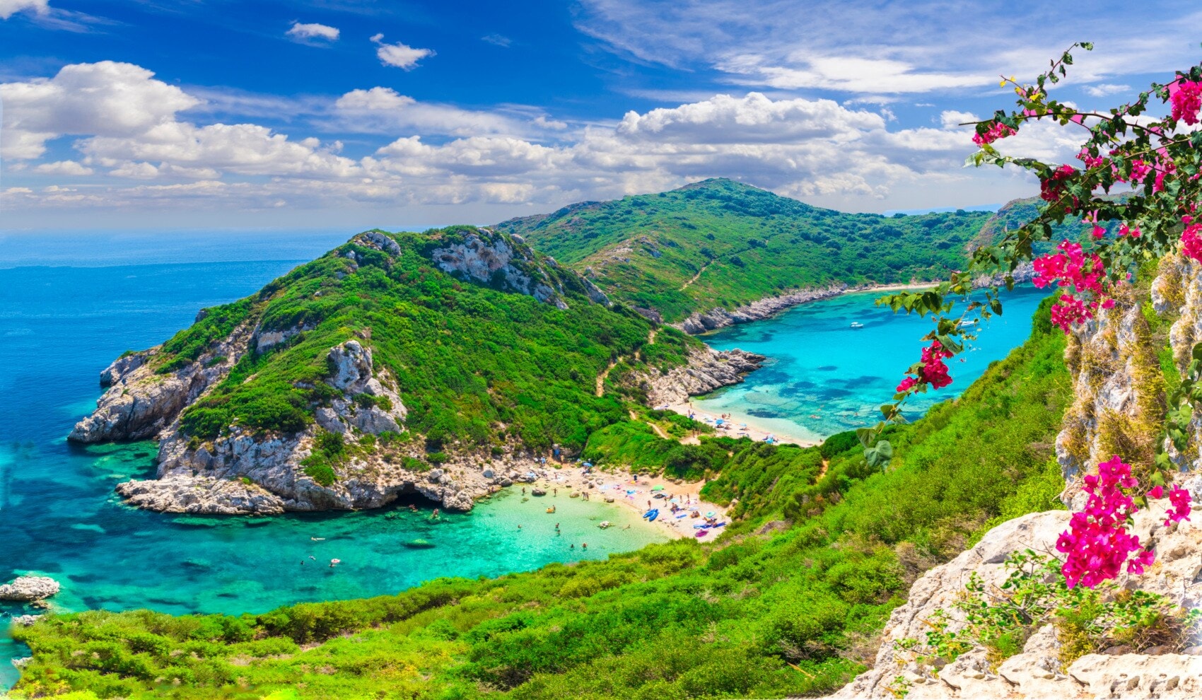 Blick auf den Timoni Beach mit türkisem Wasser und bewachsenen Bergen Blick auf den Timoni Beach mit türkisem Wasser und bewachsenen Bergen