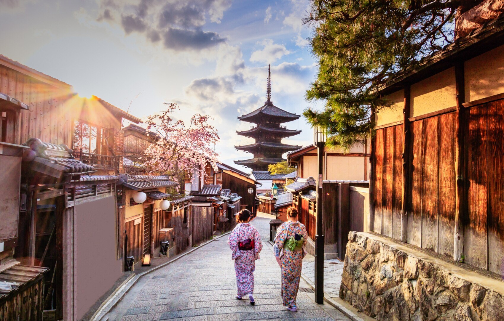Zwei Frauen in bunten Kimonos laufen durch eine Gasse in der Altstadt von Kyoto auf einen Tempel zu Zwei Frauen in bunten Kimonos laufen durch eine Gasse in der Altstadt von Kyoto auf einen Tempel zu