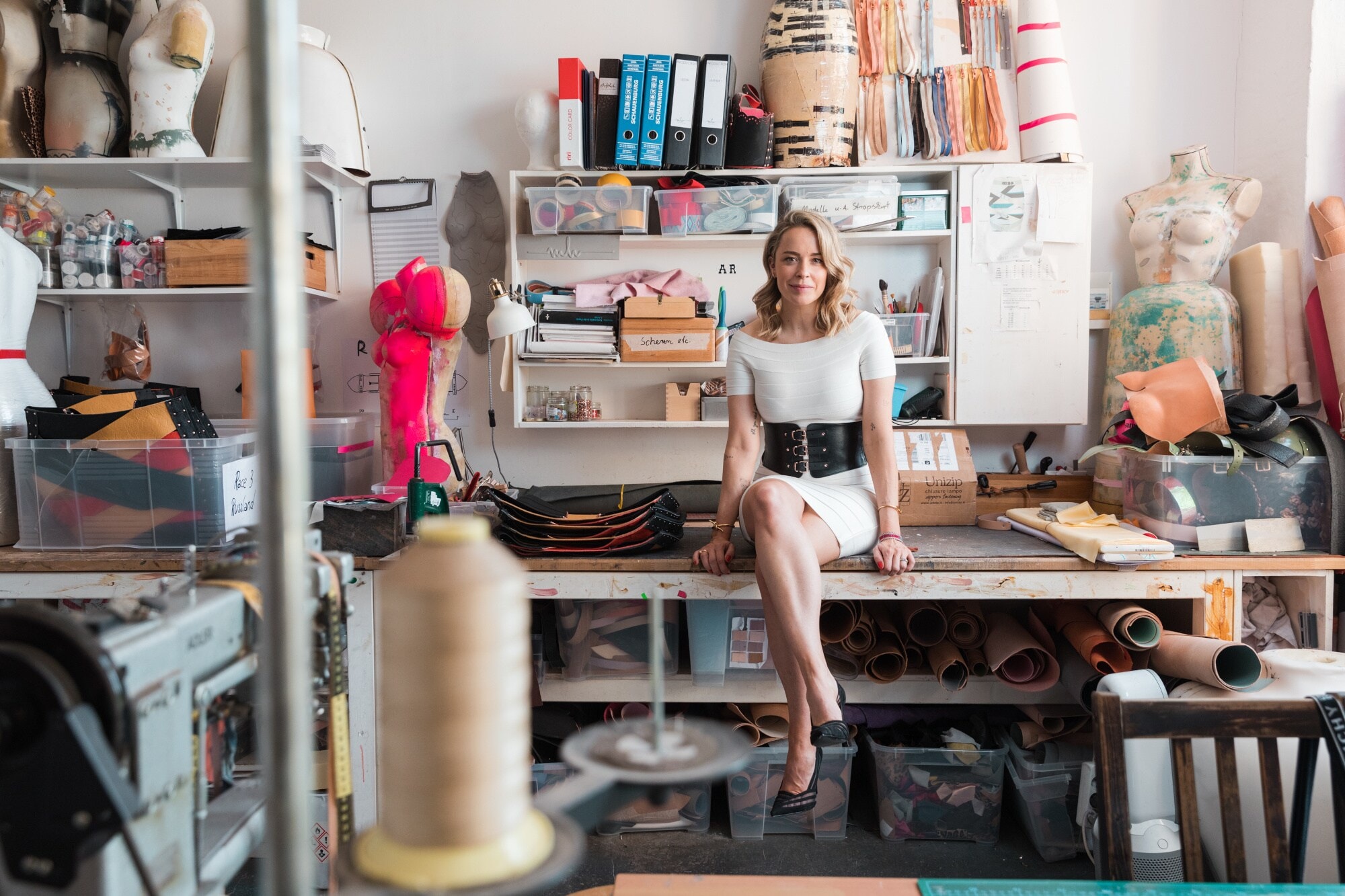 Marina Hoermanseder sitzt in ihrem Atelier auf ihrem Schreibtisch Marina Hoermanseder sitzt in ihrem Atelier auf ihrem Schreibtisch