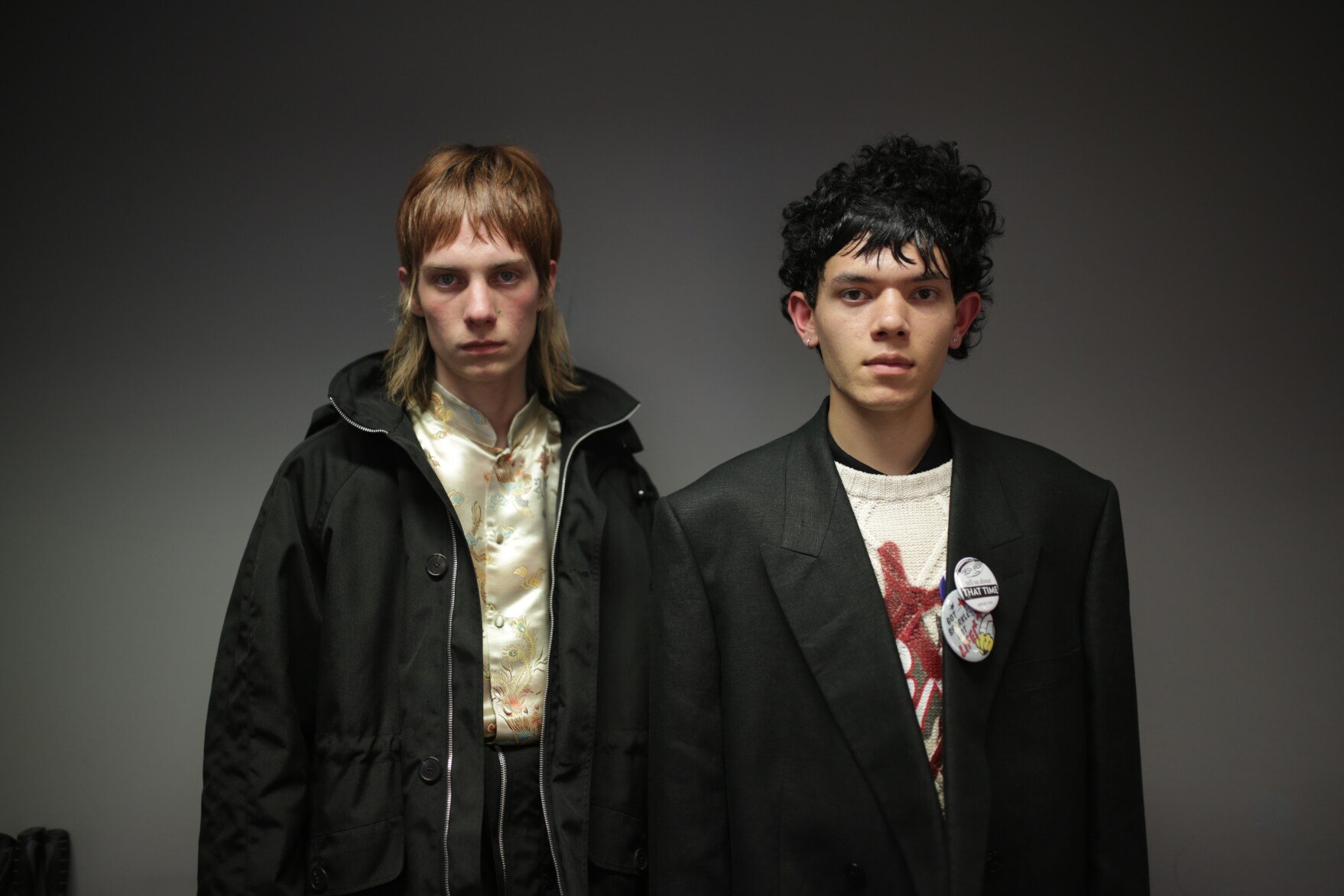 Zwei männliche Models posieren mit schwarzen Jacken und rockigen Stufenhaarschnitten