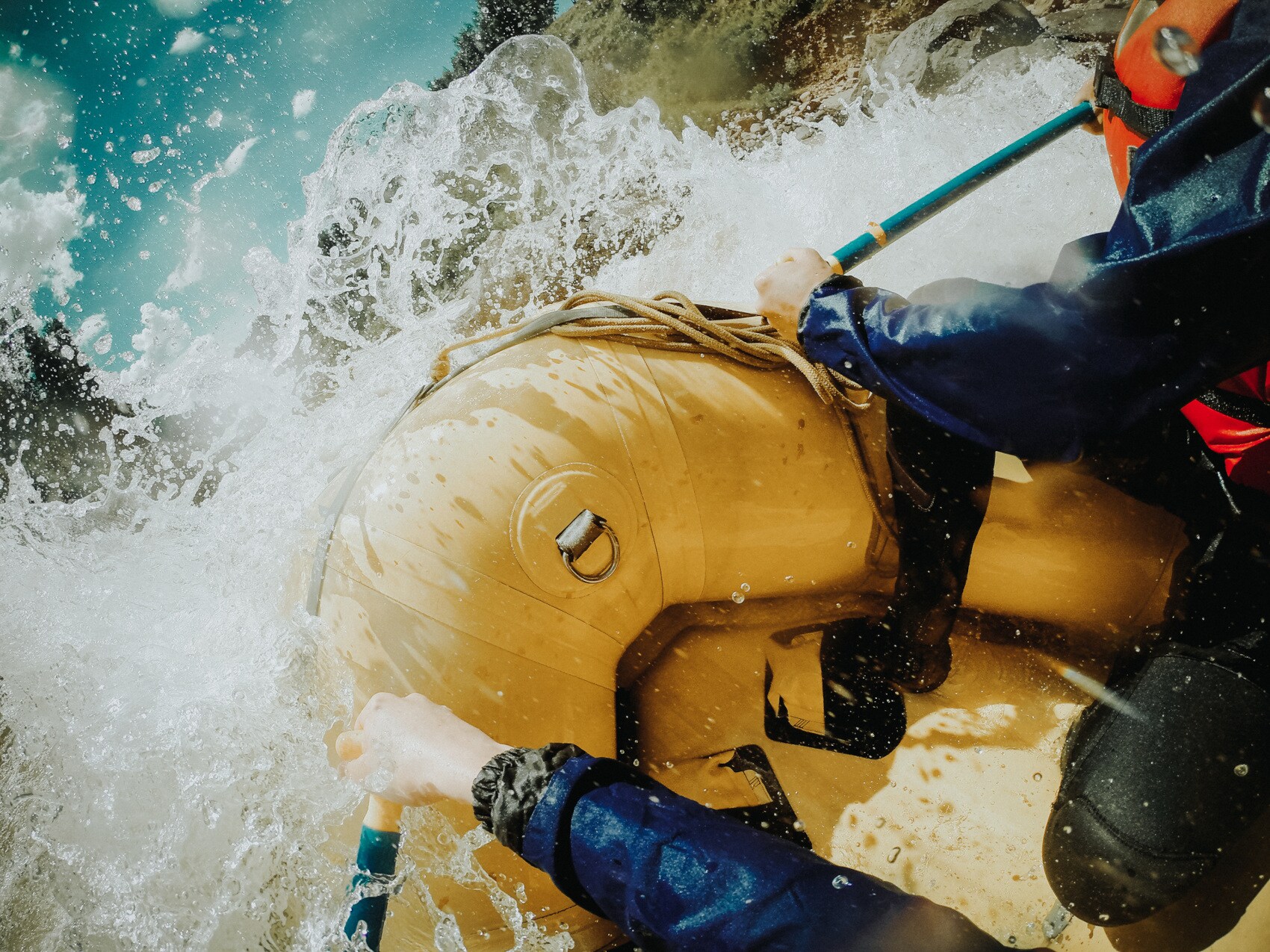 Detailaufnahme von einem Schlauchboot, in dem zwei Personen sitzen und ihre Paddel ins Wasser stoßen