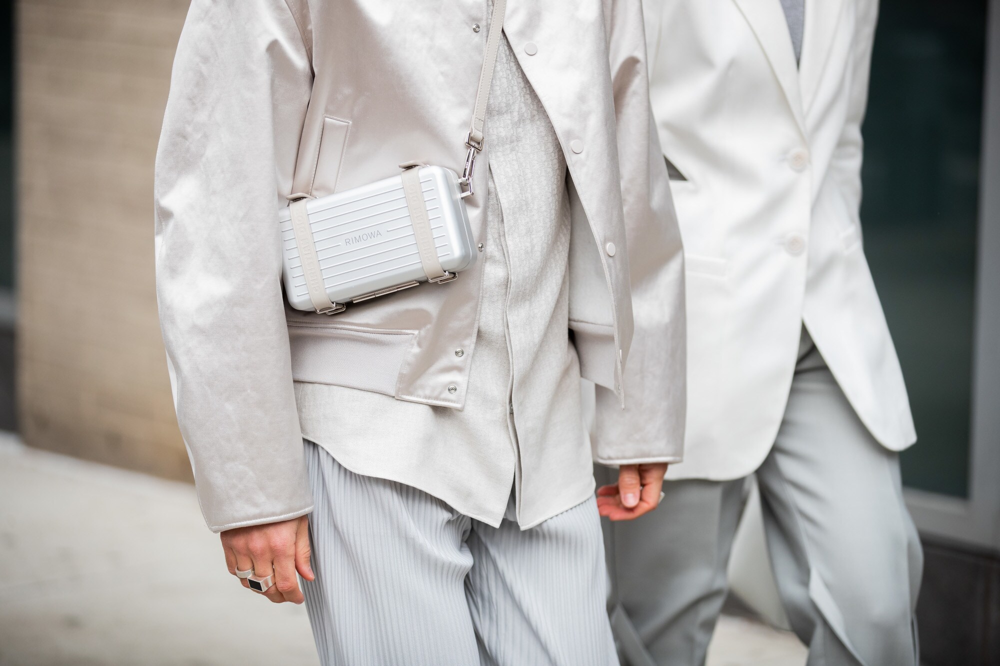 Models ins heller Businesskleidung tragen eine von Dior und Rimowa entwickelte Tasche Models ins heller Businesskleidung tragen eine von Dior und Rimowa entwickelte Tasche