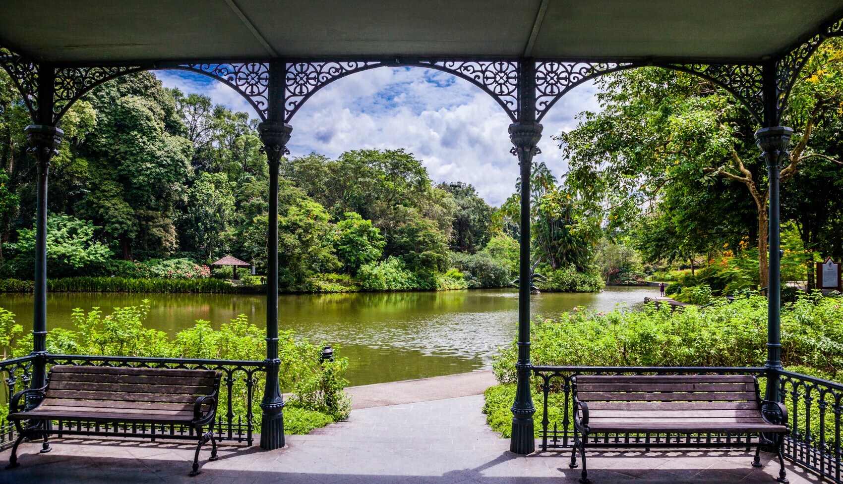 Blick auf einen See in einer grünen Parkanlage aus einem Pavillon mit Holzbänken Blick auf einen See in einer grünen Parkanlage aus einem Pavillon mit Holzbänken