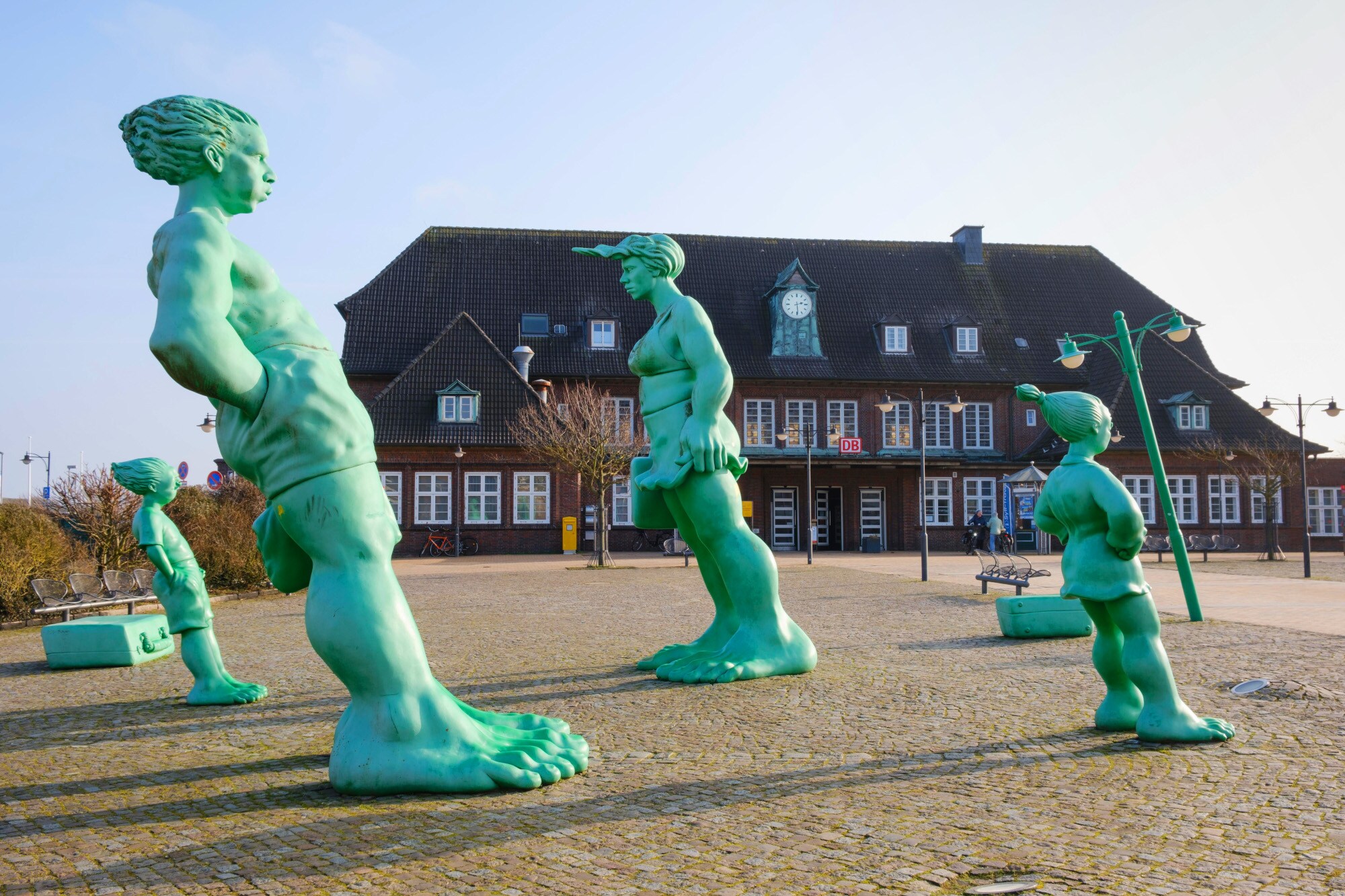 Vier grüne, übermannsgroße und schrägstehende Skulpturen auf dem Bahnhofsvorplatz in Westerland