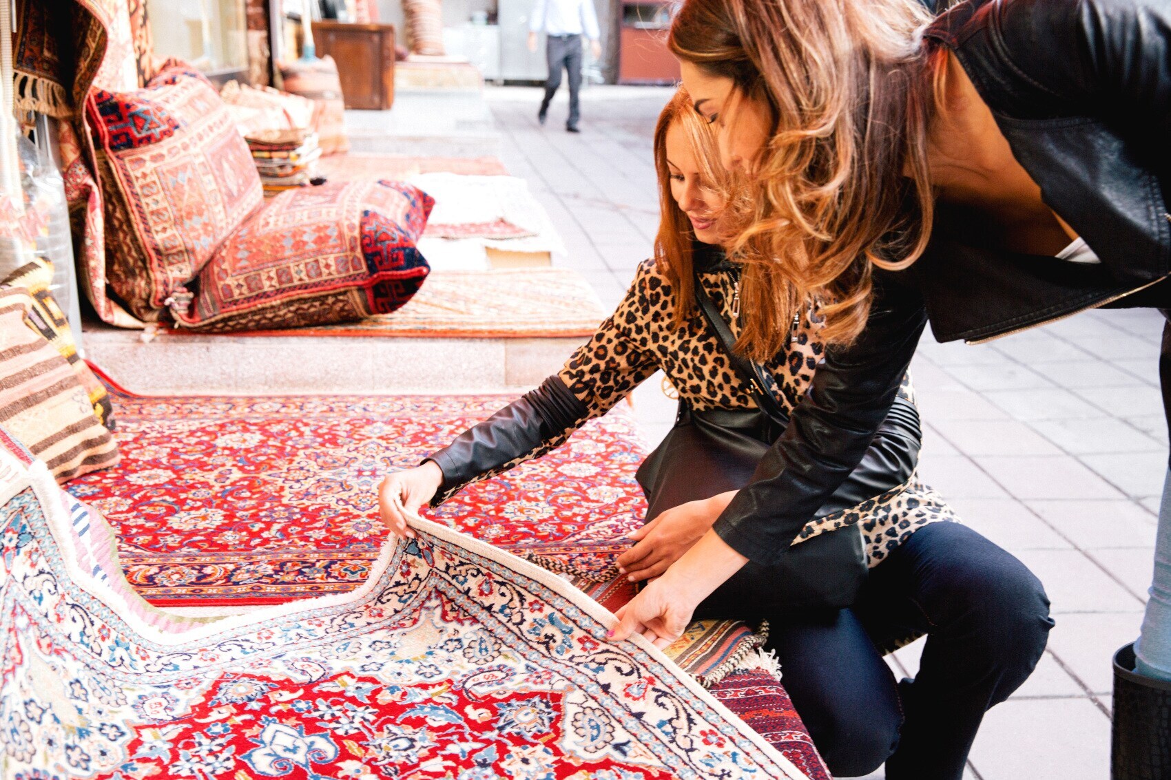 Zwei Frauen prüfen einen Perserteppich Zwei Frauen prüfen einen Perserteppich