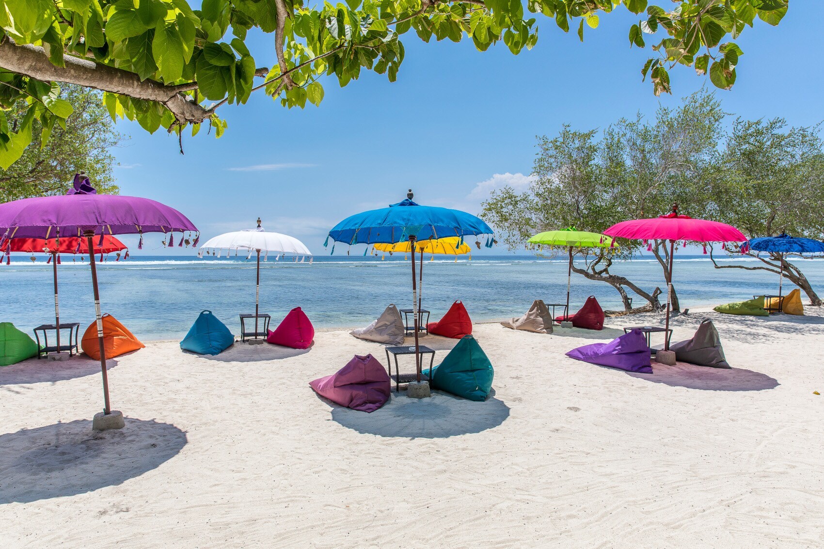 Bunte Sonnenschirme und Sitzsäcke an einem Strand auf den Gili Islands nahe Bali