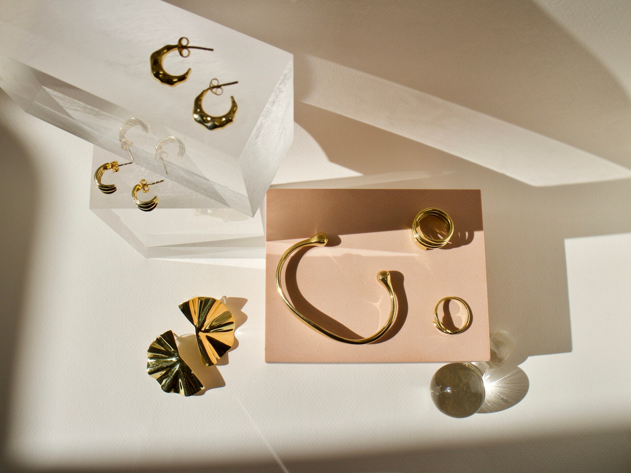 Feiner Goldschmuck liegt auf transparenten Glaswürfeln.