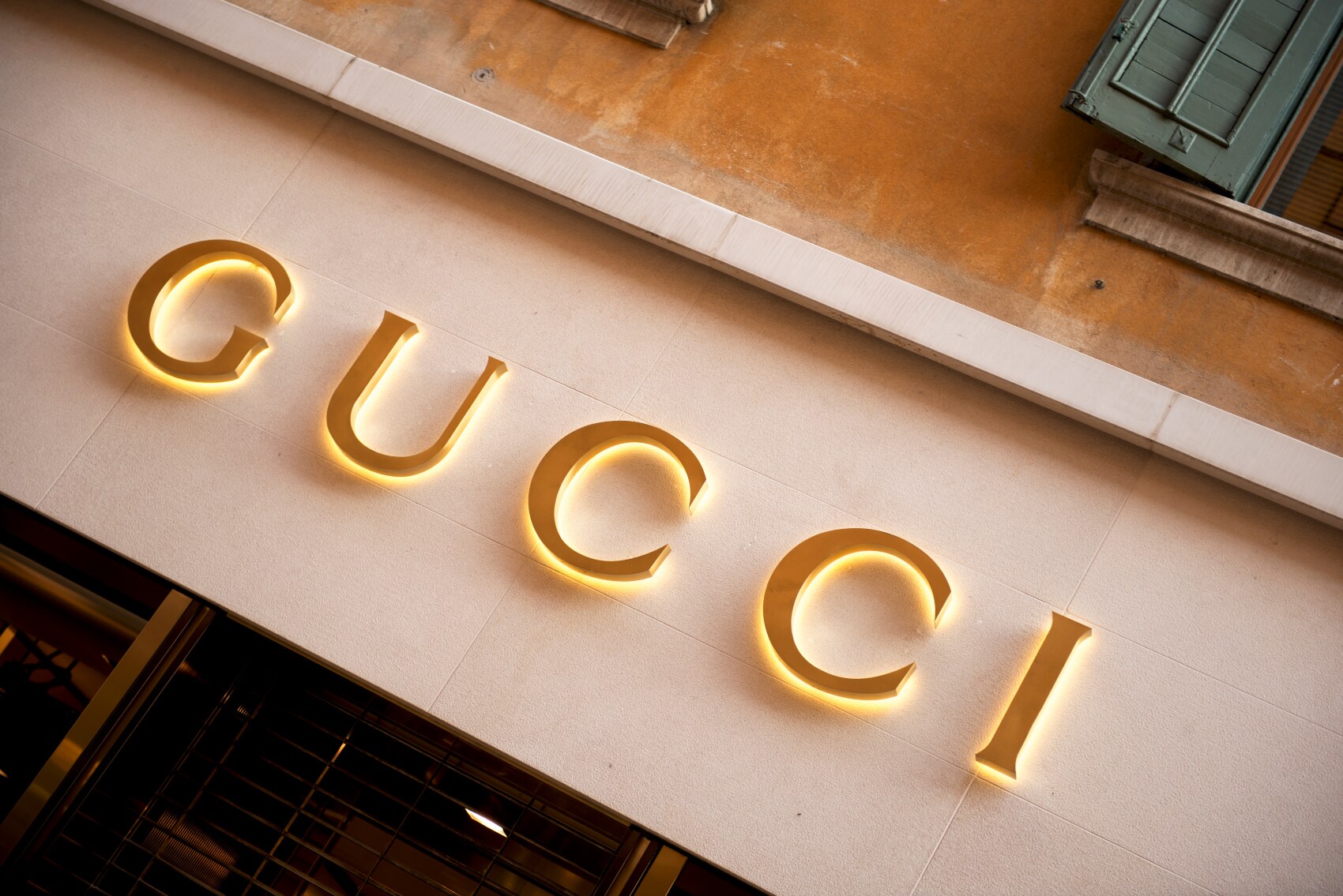 Das Logo von Gucci in Goldlettern an einer mediterranen Hausfassade Das Logo von Gucci in Goldlettern an einer mediterranen Hausfassade