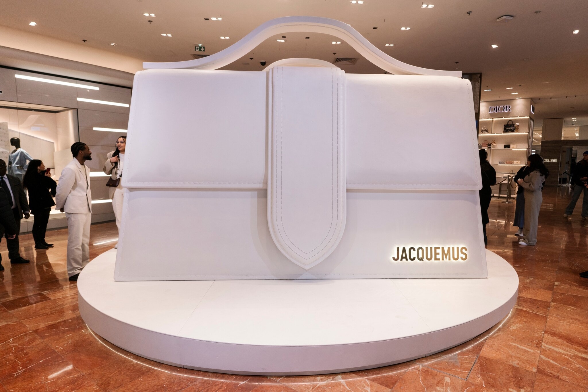 Alt-Text: Eine weiße, überdimensionale Le Bambino-Tasche des Designers Jacquemus in der Pariser Galeries Lafayette. Alt-Text: Eine weiße, überdimensionale Le Bambino-Tasche des Designers Jacquemus in der Pariser Galeries Lafayette.
