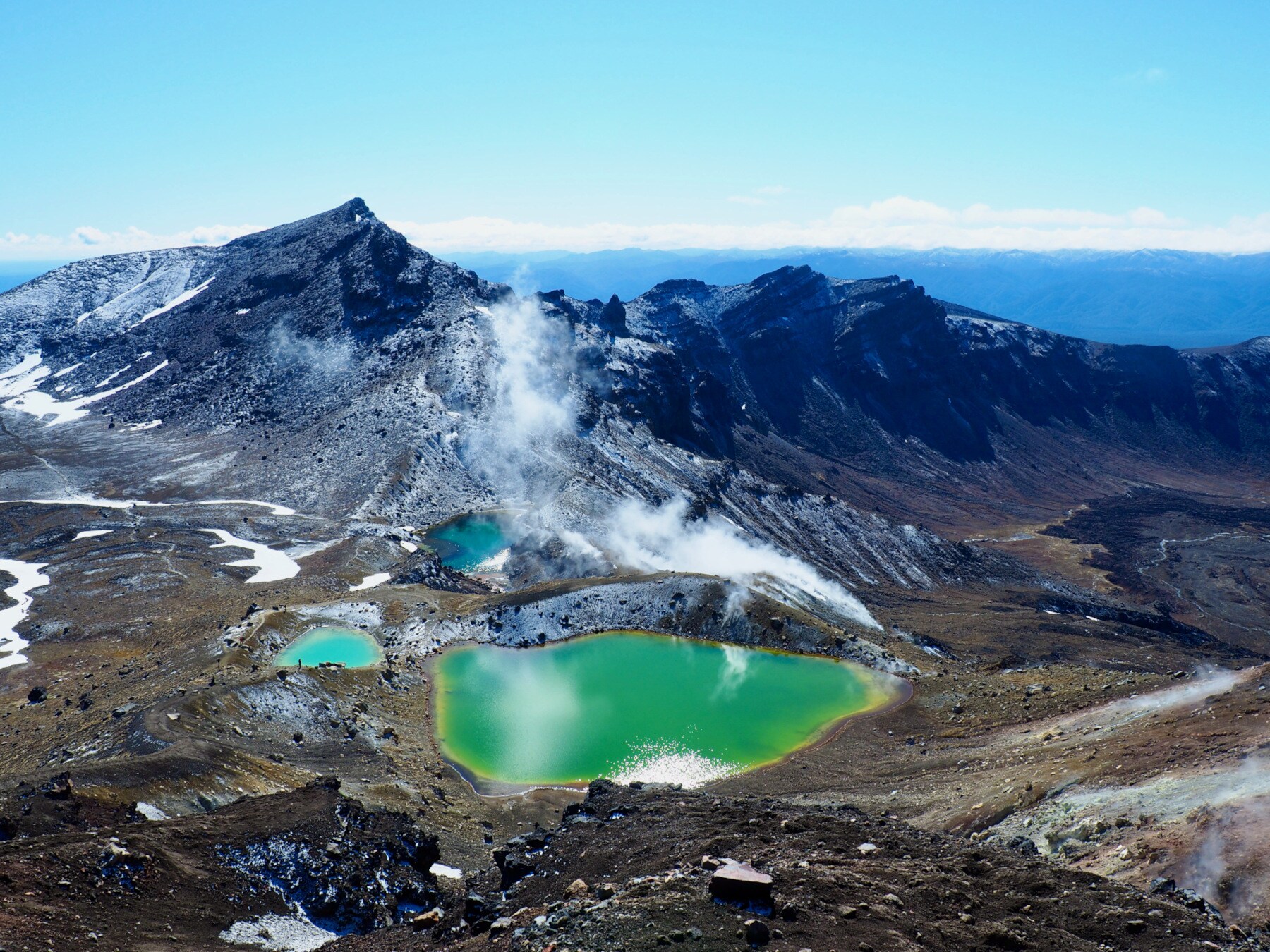 Vulkanlandschaft mit grünen Bergseen und hervorsteigendem Wasserdampfwolken