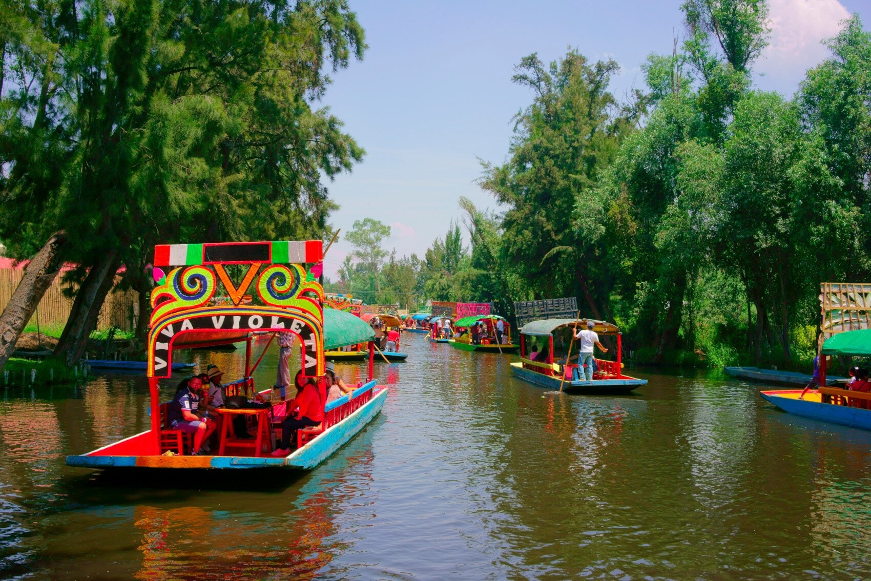 Bunte Ausflugsboote fahren auf einen begrünten Kanal Bunte Ausflugsboote fahren auf einen begrünten Kanal