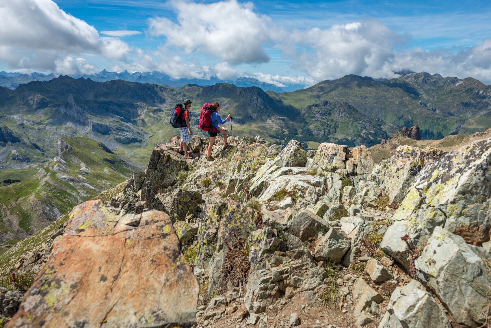 Zwei Wandernde mit Rucksäcken auf einem Gipfel vor Bergpanorama Zwei Wandernde mit Rucksäcken auf einem Gipfel vor Bergpanorama