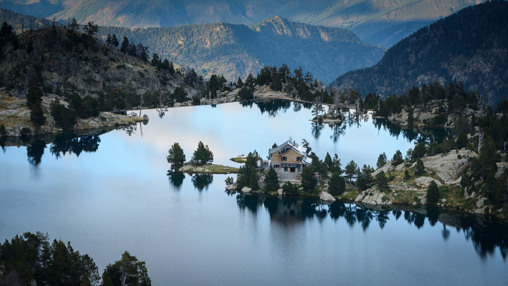 Idyllische Berglandschaft mit See, an dem eine einzelne Hütte steht
