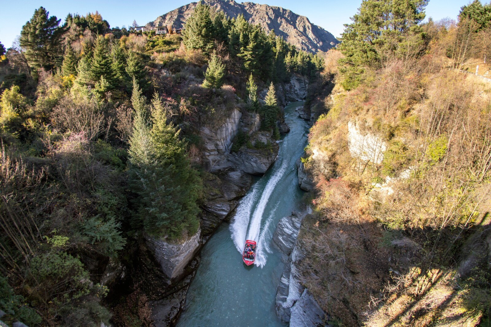 Blick von oben auf ein rotes Boot auf dem Shotover River Blick von oben auf ein rotes Boot auf dem Shotover River
