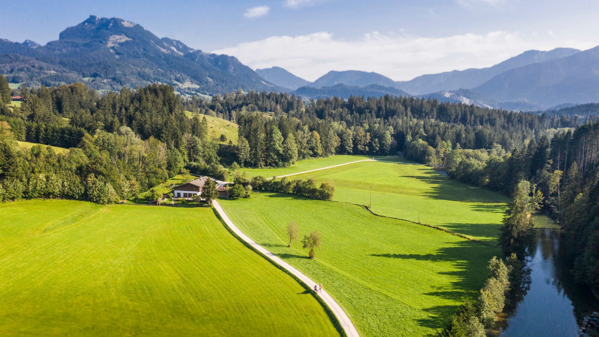 Blick auf eine Landschaft mit Bergen, Wiesen und einem Bach Blick auf eine Landschaft mit Bergen, Wiesen und einem Bach