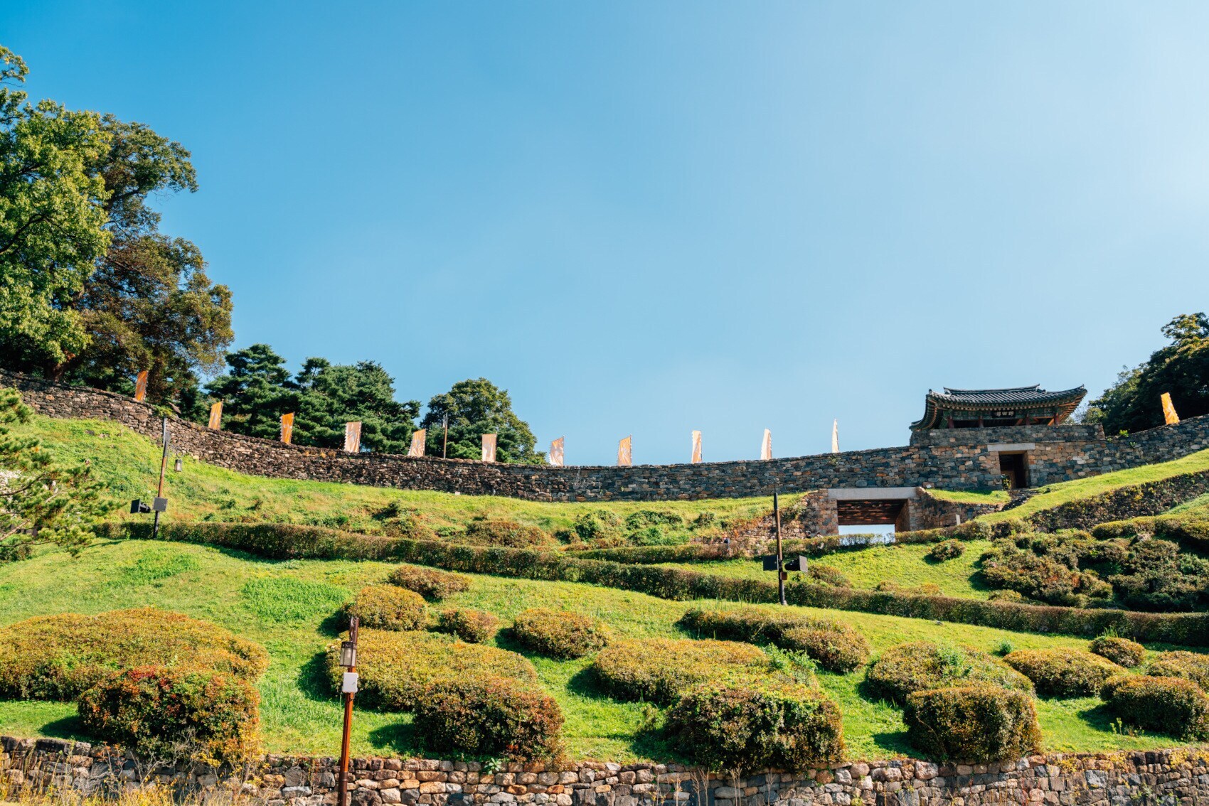 Eine begrünte Festungsanlage mit Steinmauer und Stadttor im koranischen Baustil