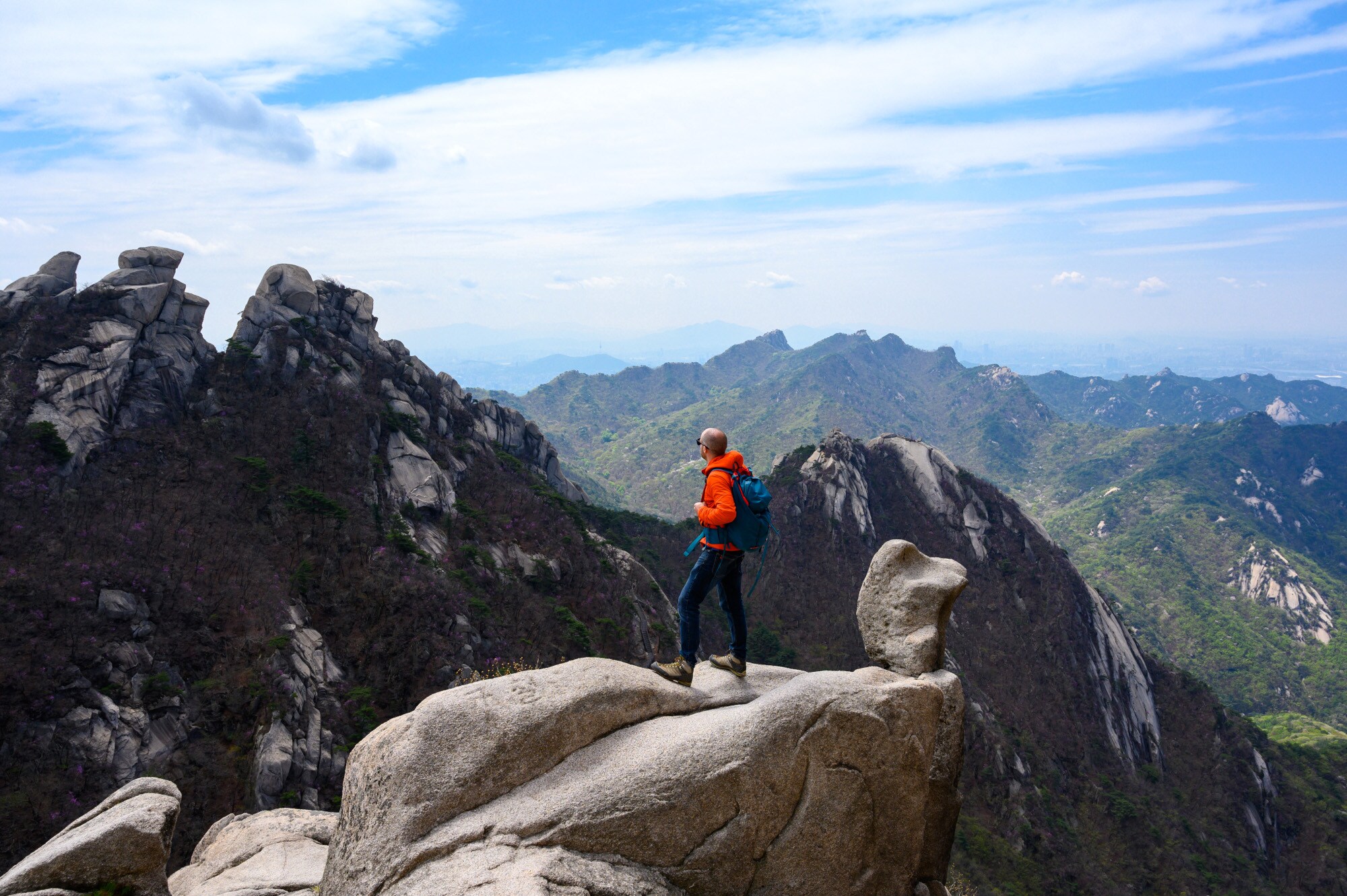 Ein Wanderer steht auf einem Felsgipfel und blickt über die Landschaft im Bukhansan Nationalpark