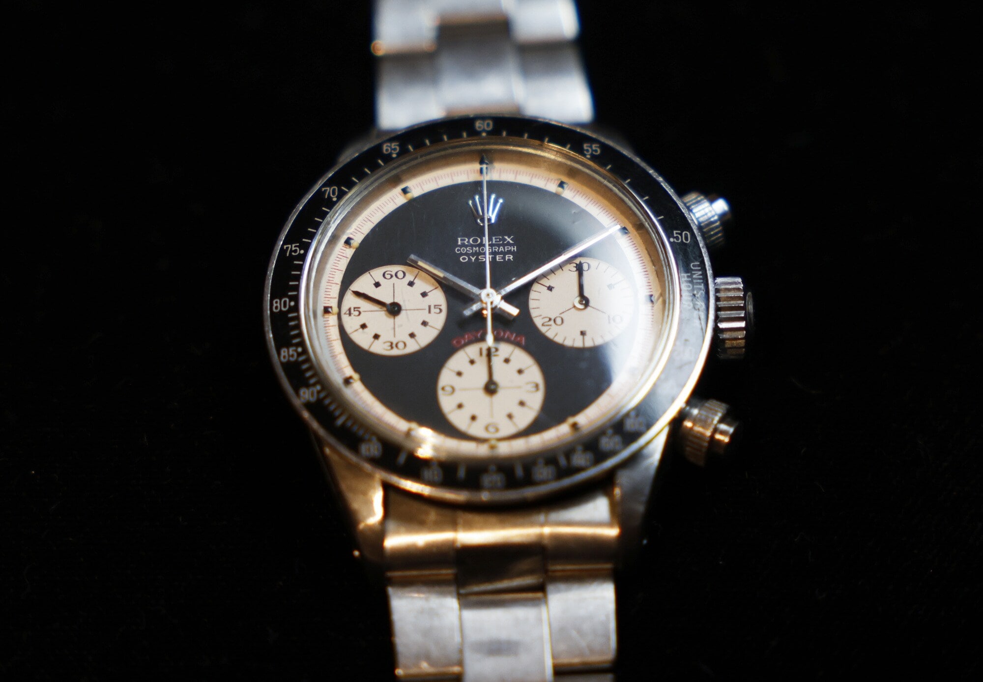 Nahaufnahme einer alten Rolex-Uhr, Modell Cosmograph Daytona Oyster mit schwarz-hellgelbem Zifferblatt und Metallarmband Nahaufnahme einer alten Rolex-Uhr, Modell Cosmograph Daytona Oyster mit schwarz-hellgelbem Zifferblatt und Metallarmband