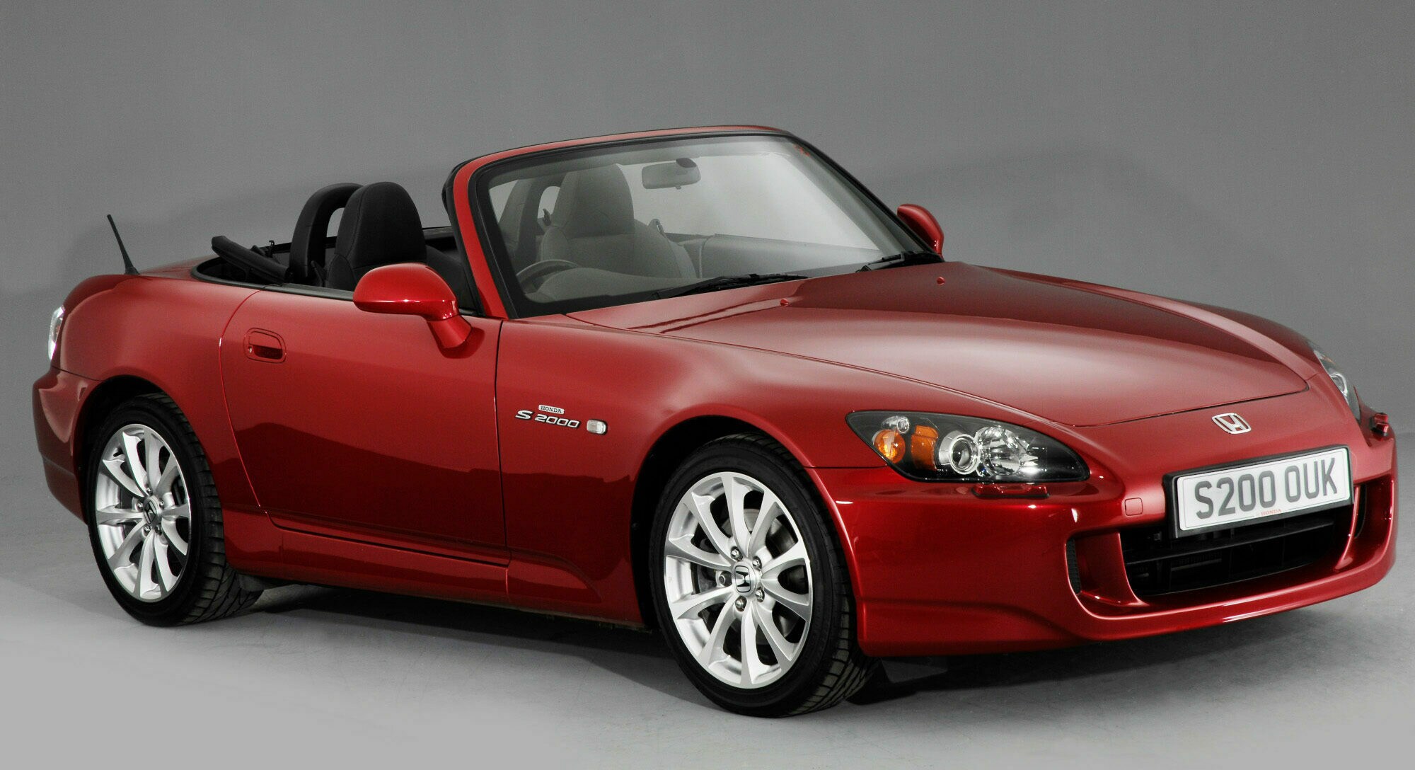 Studioaufnahme eines roten Honda S2000 vor grauem Hintergrund